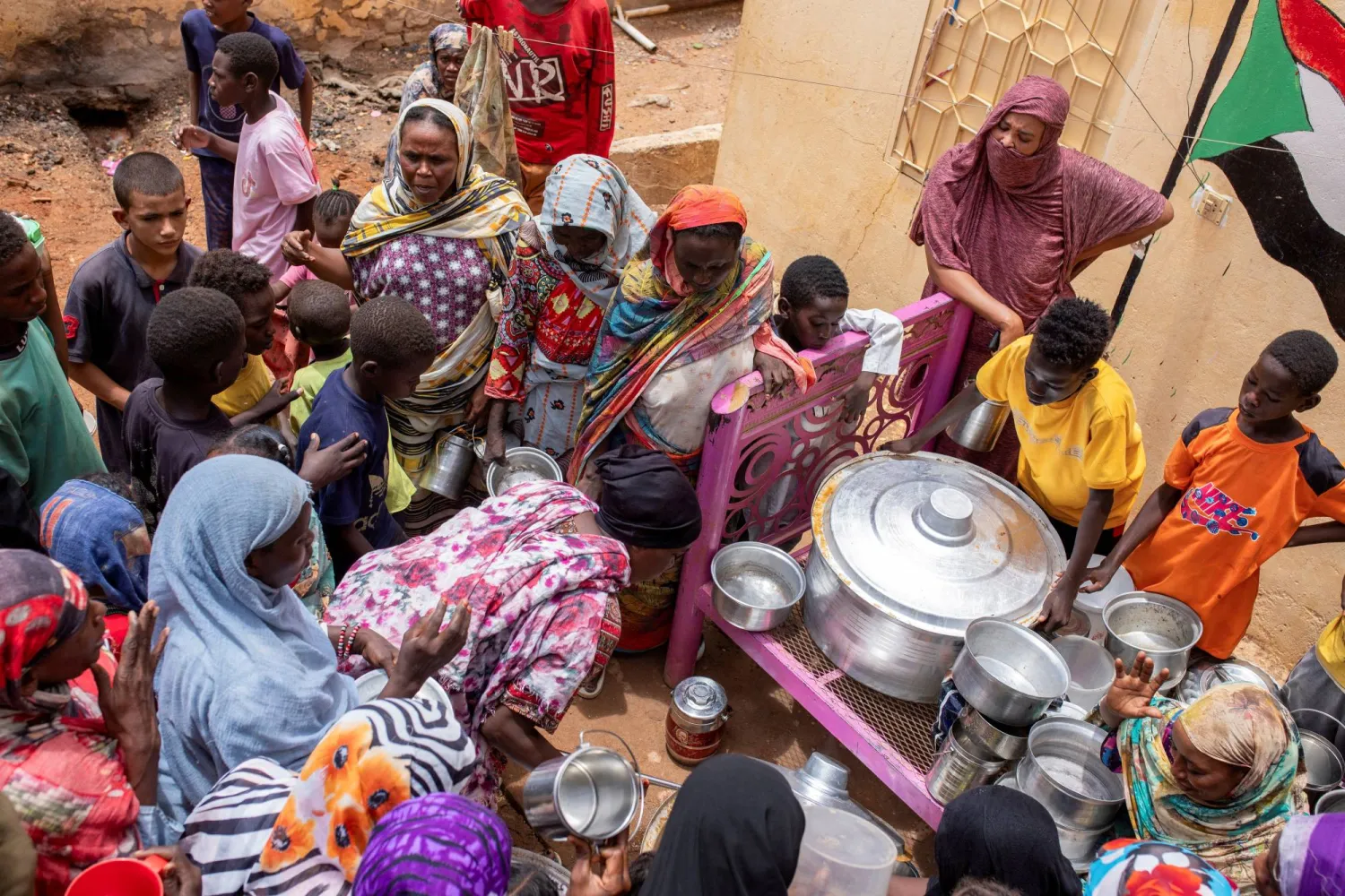 سودانيات يوزعن وجبات الطعام على الأشخاص المتضررين من النزاع والجوع الشديد في أم درمان (رويترز)