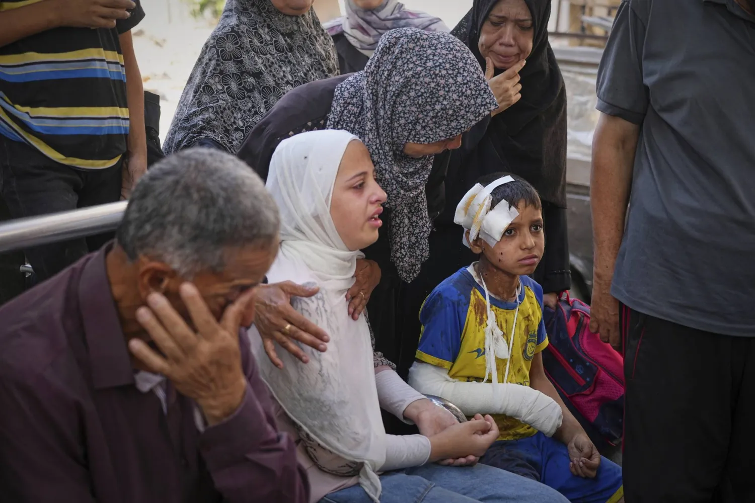 طفل مصاب مع أسرته يجلسون في انتظار جنازة والده الذي قُتل خلال قصف إسرائيلي على قطاع غزة (أ.ب)
