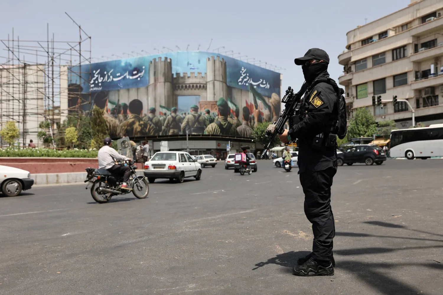 حارس أمن في شارع بطهران أمس مع بدء سريان اتفاق وفق النار بين إيران وإسرائيل (رويترز)