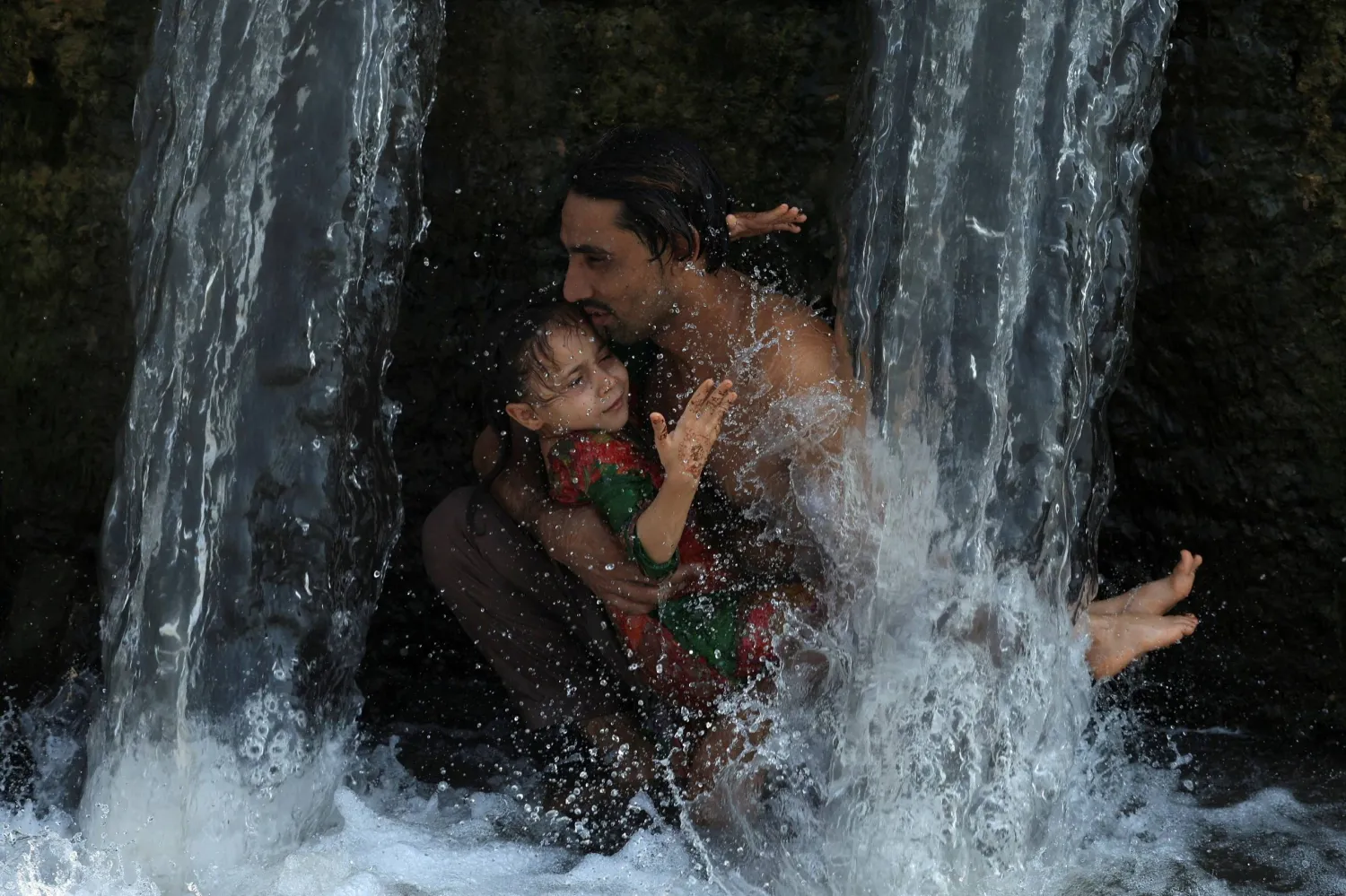 رجل يبرد جسمه وطفلته في بيشاور بباكستان وسط درجات مرتفعة (رويترز)