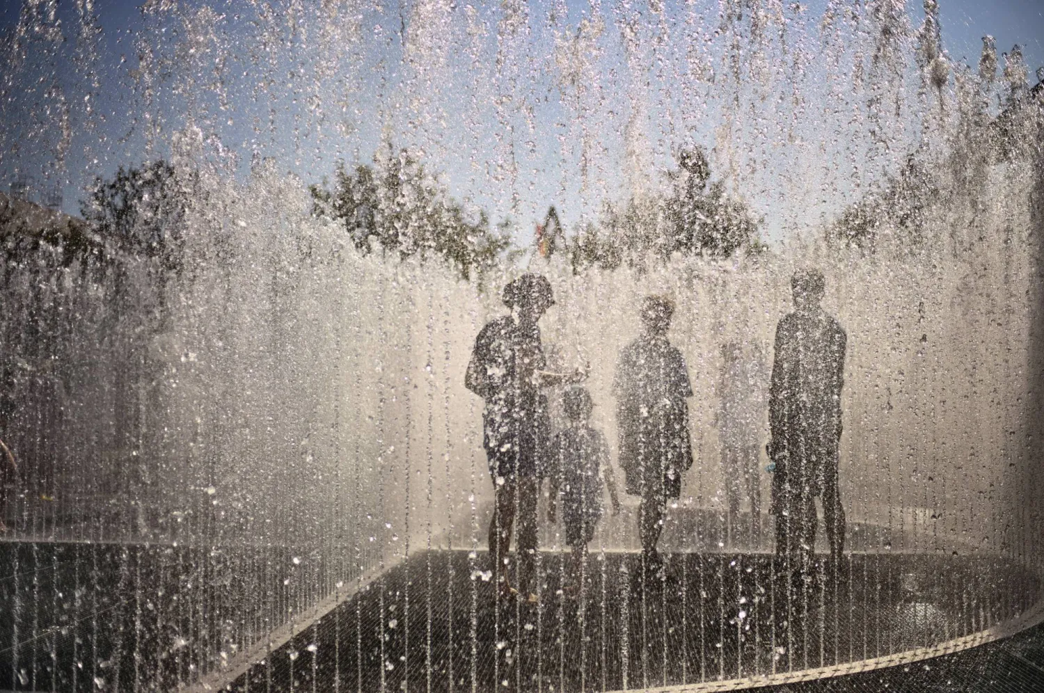 أشخاص يحاولون تبريد أنفسهم داخل نافورة في بون بألمانيا وسط ارتفاع درجات الحرارة (أ.ب)