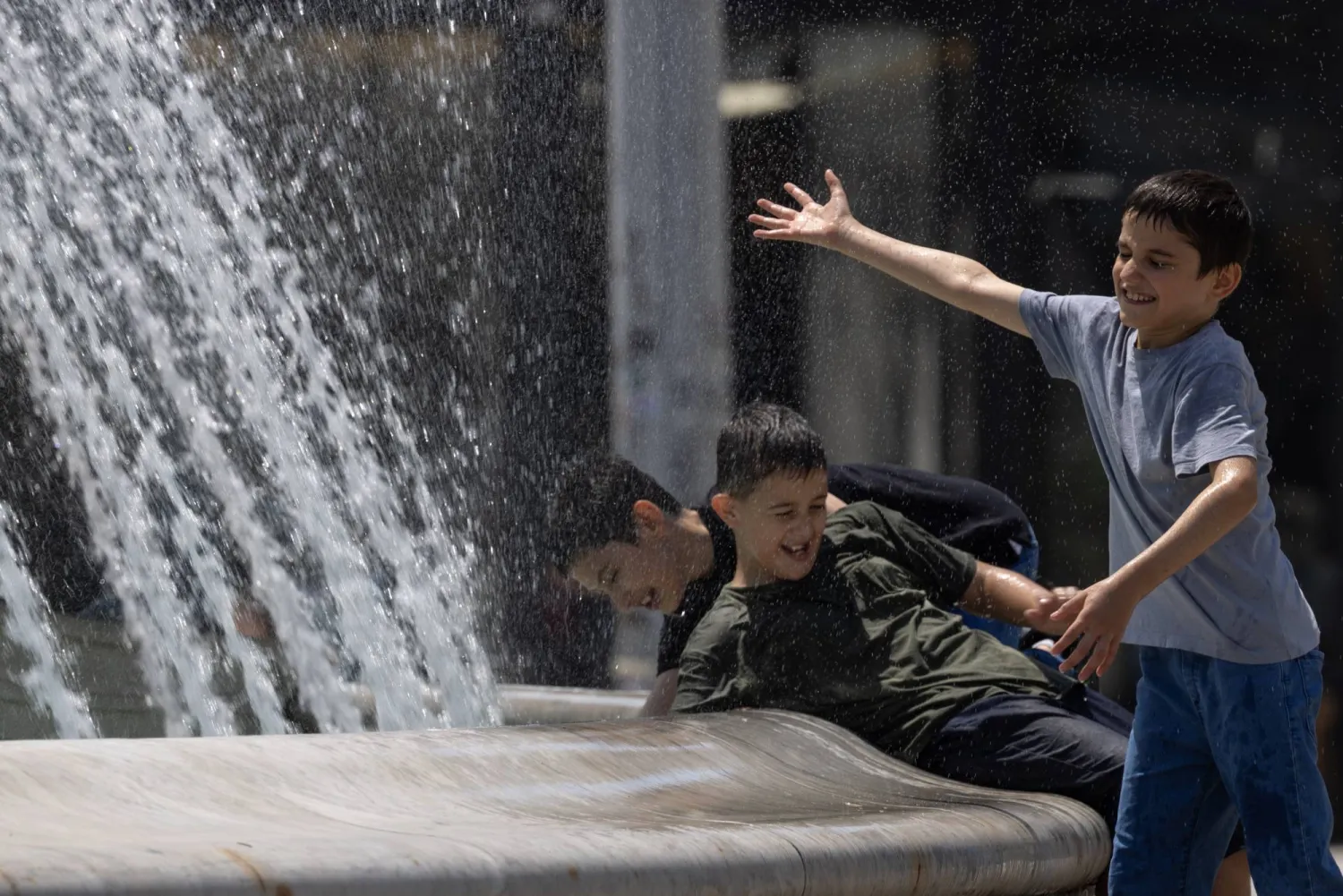 أطفال يلعبون بجوار نافورة مياه في مقدونيا الشمالية (إ.ب.أ)