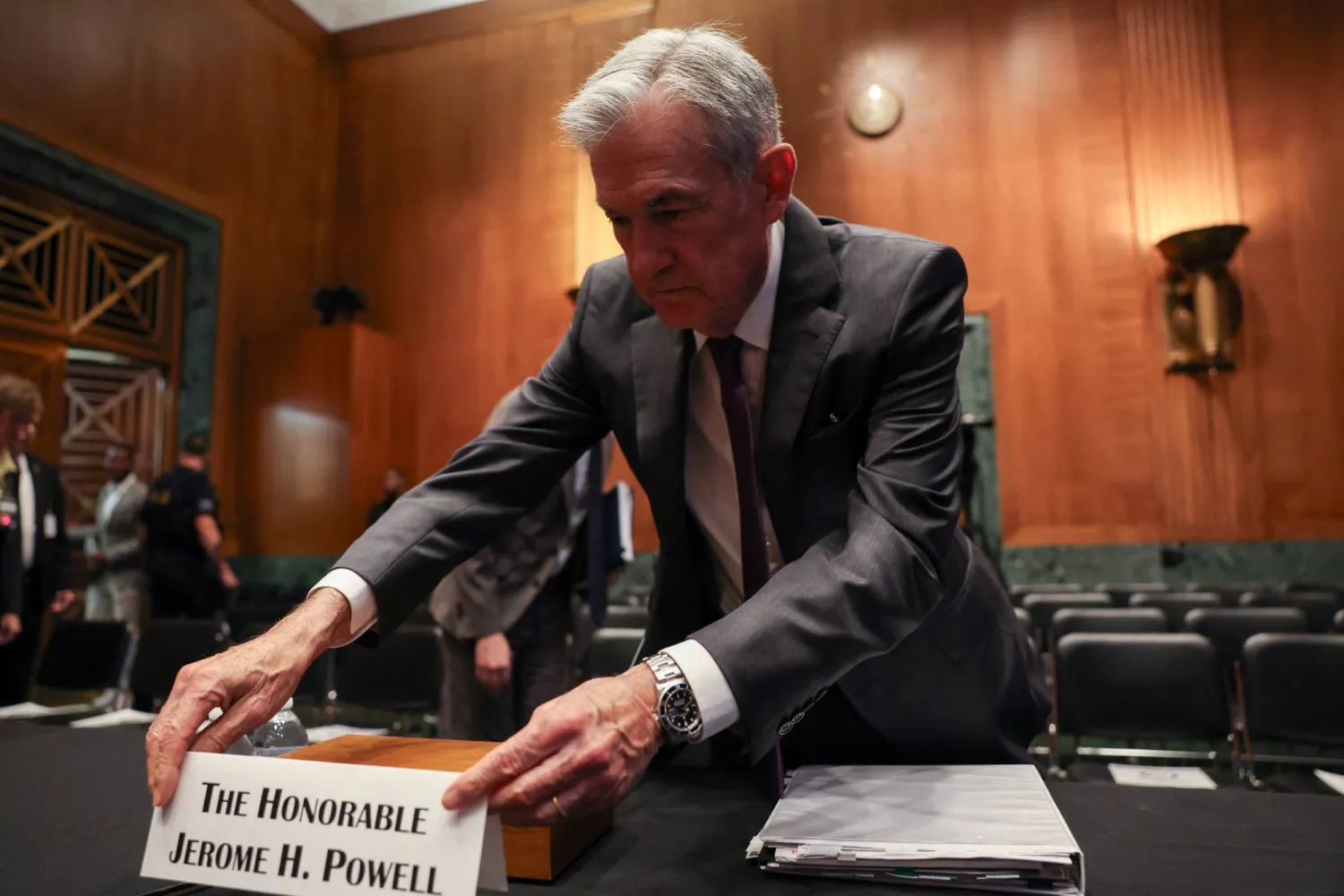 رئيس مجلس الاحتياطي الفيدرالي جيروم باول يُعدّل بطاقة تعريفية لدى حضور جلسة استماع أمام لجنة الشؤون المصرفية بمجلس الشيوخ (رويترز)