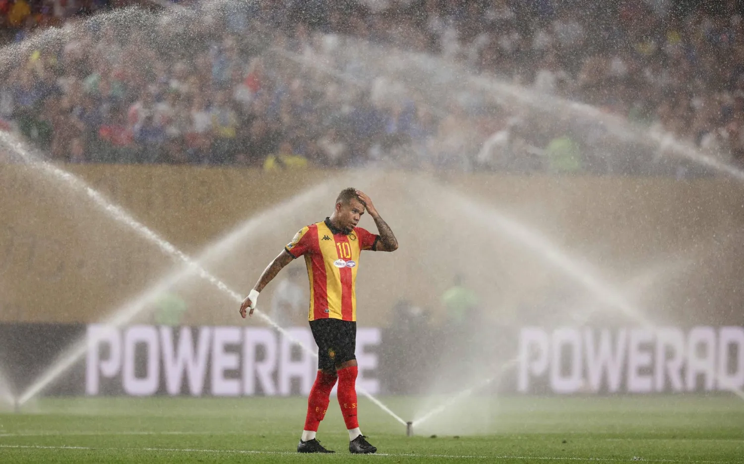 ساسي لاعب الترجي يقف بجوار رشاش الملعب لتبريد جسمه خلال وقت التوقف (ا ف ب) 