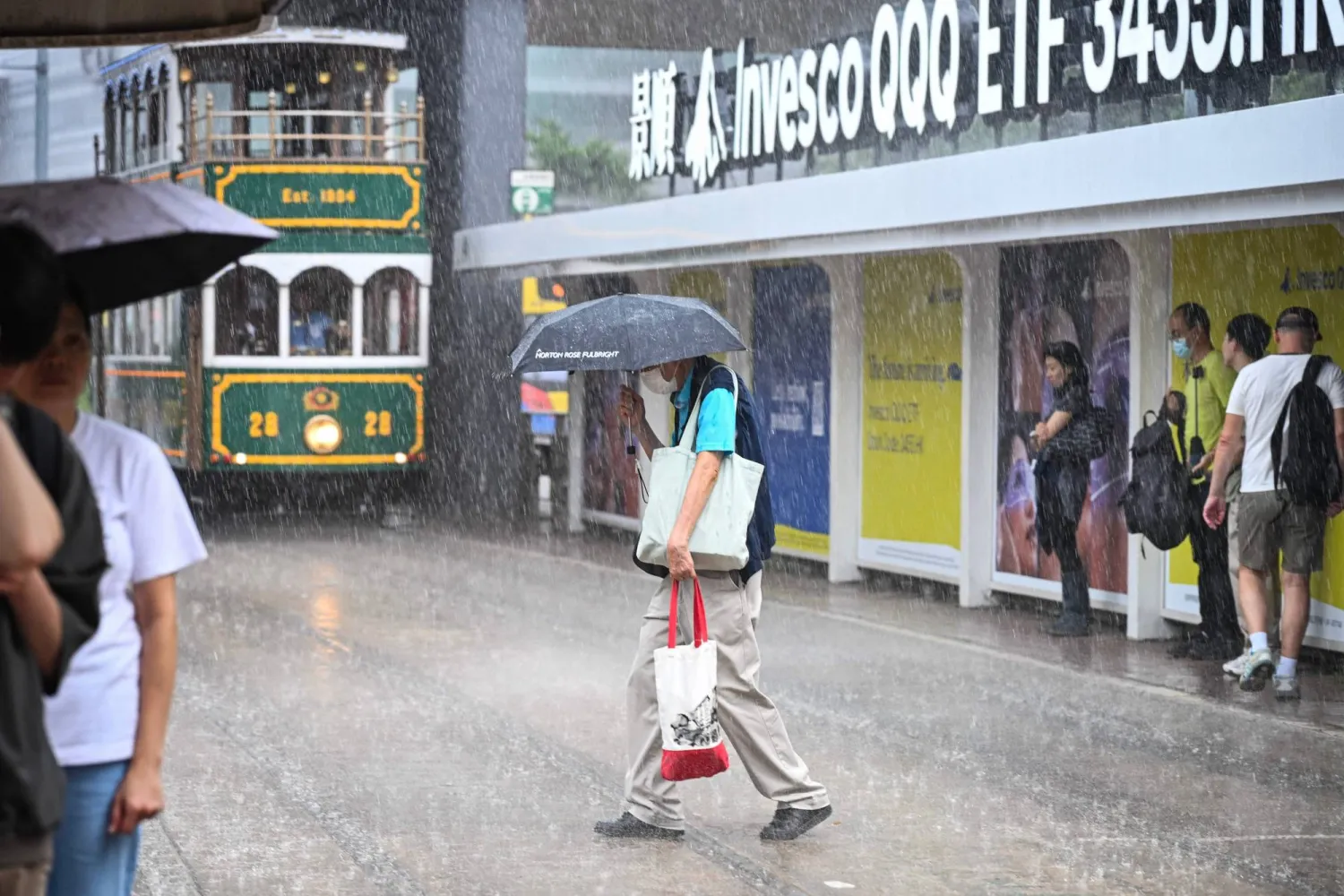 رجل يستخدم مظلة تحت الأمطار الغزيرة في جزيرة هونغ كونغ الصينية (أ.ف.ب)