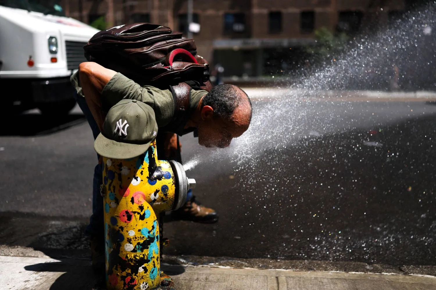 رجل يشرب المياه في الشارع بمدينة نيويورك وسط ارتفاع درجات الحرارة (أ.ف.ب)