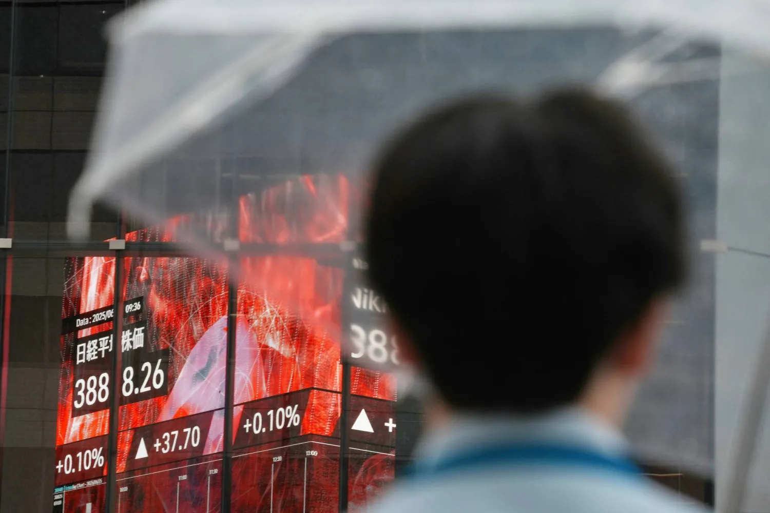 رجل ينظر إلى شاشة إلكترونية تعرض حركة الأسهم في وسط العاصمة اليابانية طوكيو (أ.ب)