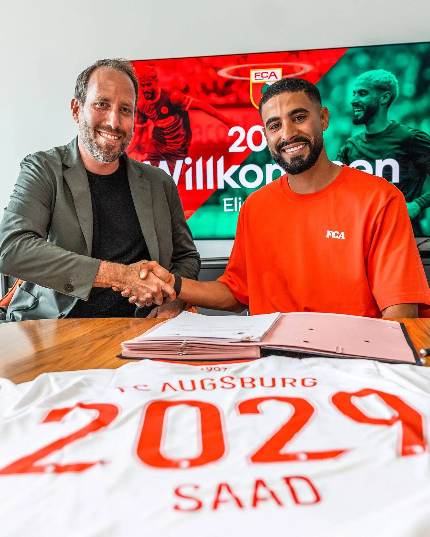 إلياس يصافح مسؤول نادي أوغسبورغ بعد توقيع العقد (نادي أوغسبورغ)