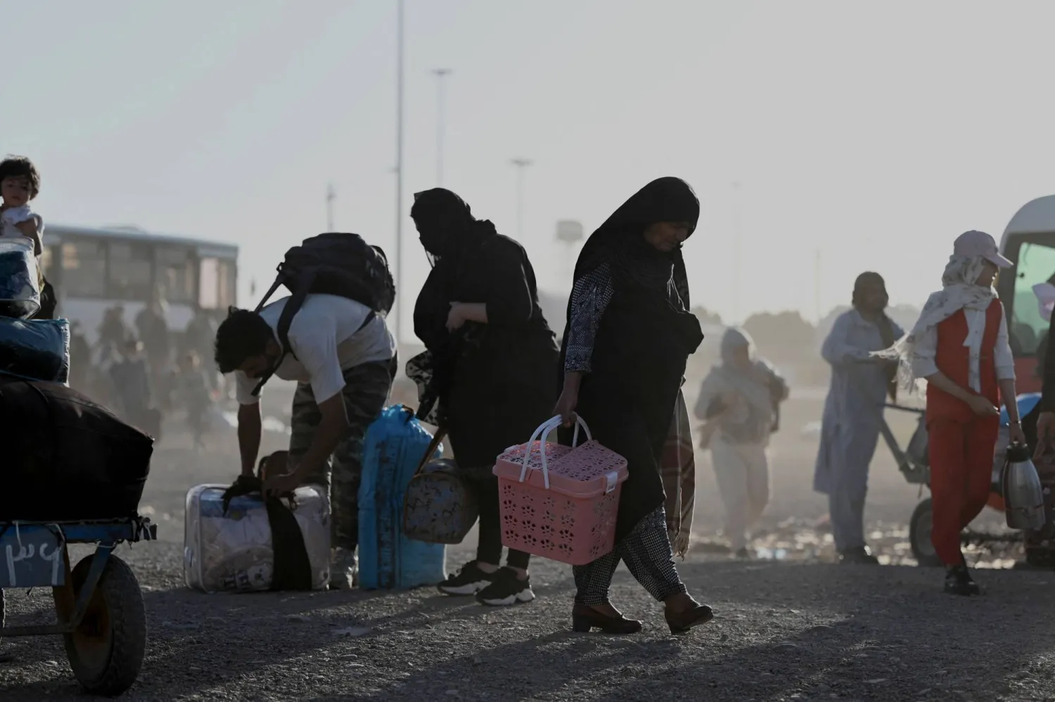لاجئون أفغان يحملون أمتعتهم لدى وصولهم إلى نقطة الصفر في معبر إسلام قلعة الحدودي بين أفغانستان وإيران في 28 يونيو 2025 بعد ترحيلهم من إيران (أ.ف.ب)