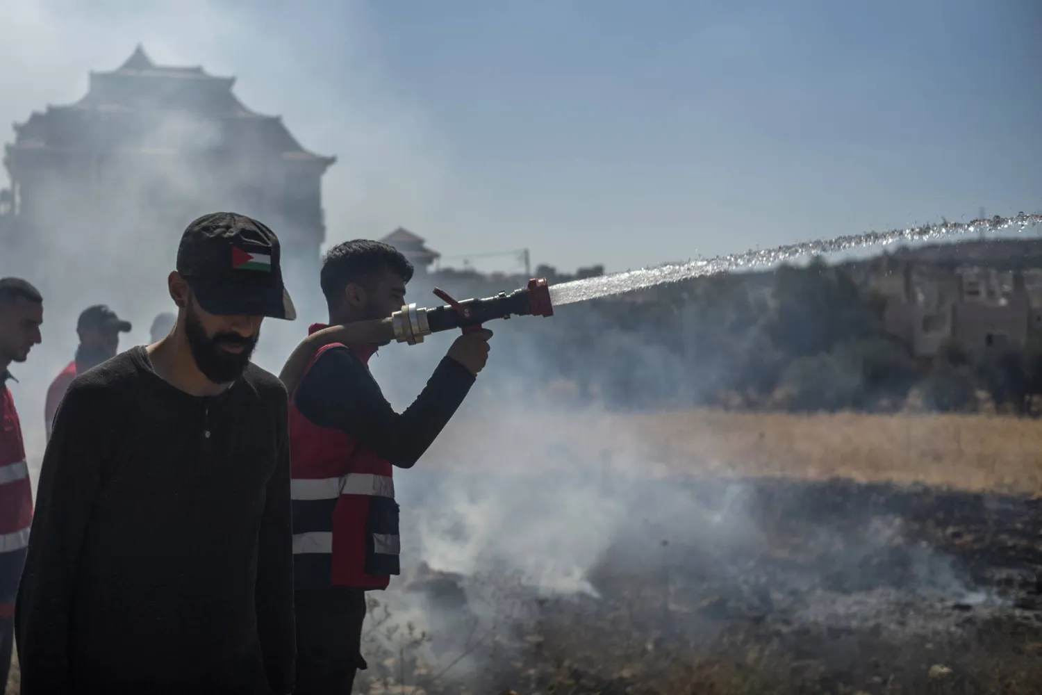 محاولات لإخماد حريق اندلع خلال هجوم شنّه مستوطنون إسرائيليون على قرية بالضفة الغربية (د.ب.أ)