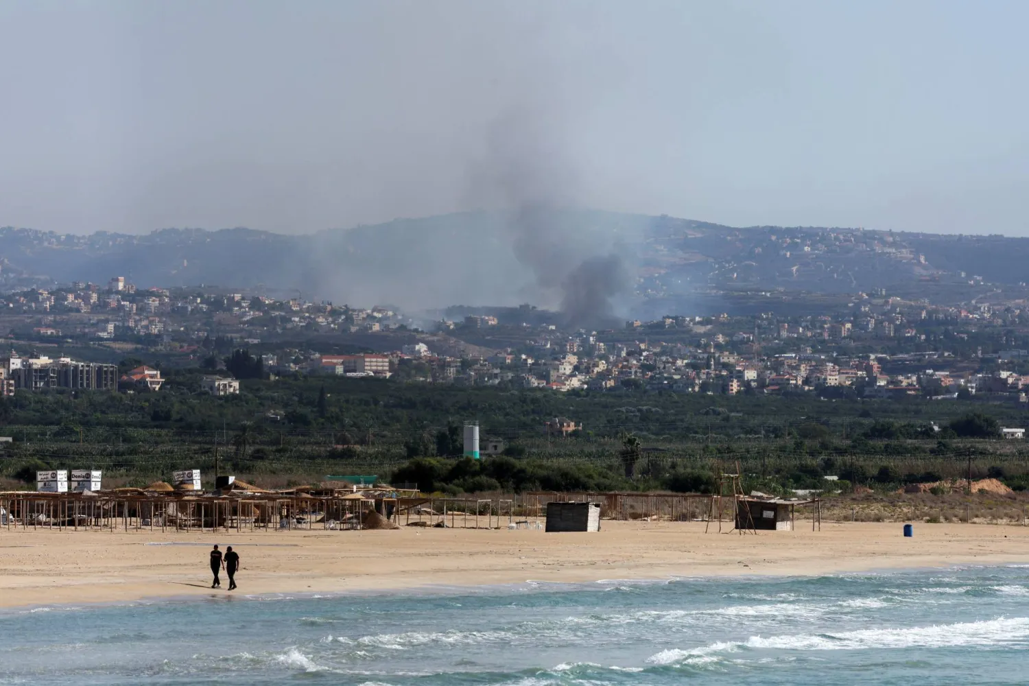 شاطئ مدينة صور ويظهر في الخلفية دخان يتصاعد جراء غارة إسرائيلية في أكتوبر 2024 (رويترز)
