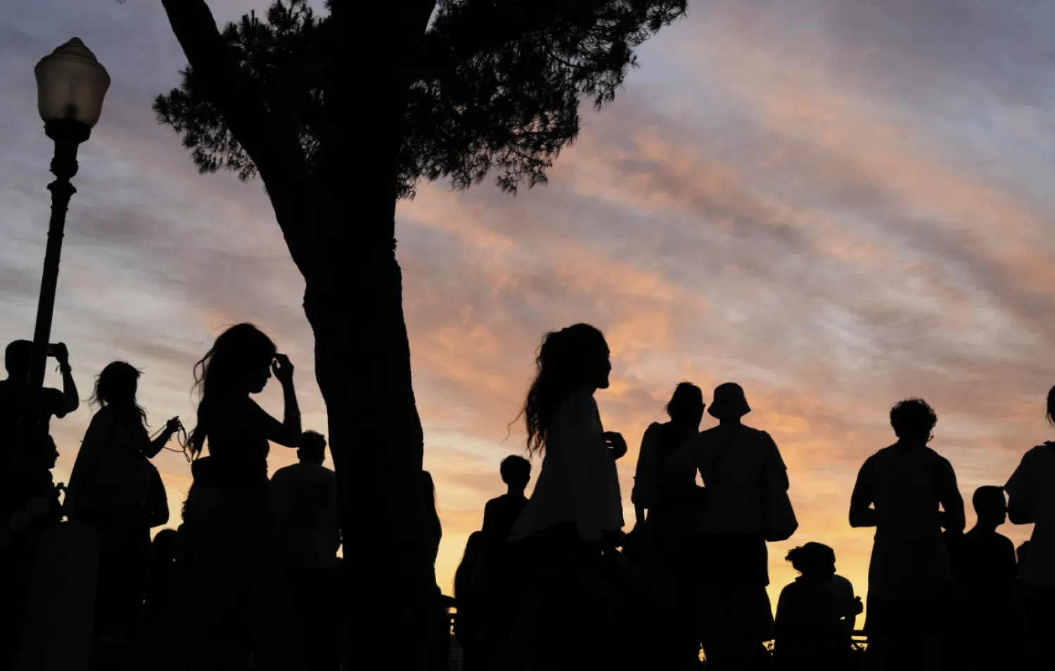 People watch the sun set from the Our Lady of the Hill viewpoint overlooking Lisbon at the end of a hot day in Lisbon, Friday, June 27, 2025. (AP Photo/Armando Franca)
