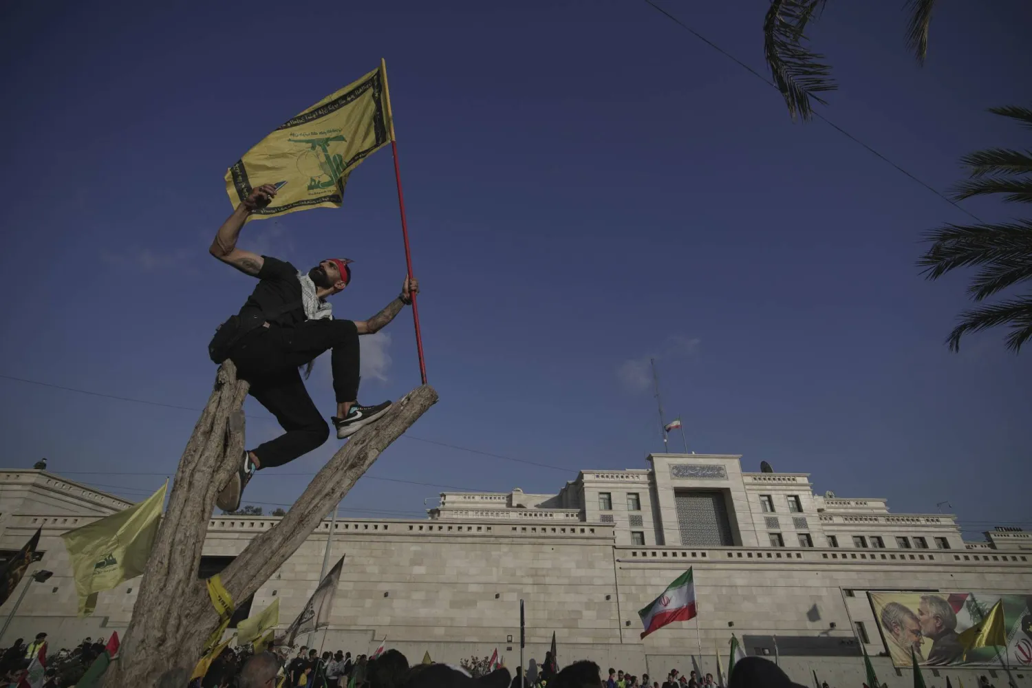 مُناصر لـ«حزب الله» يرفع عَلمه ويلتقط صورة قرب السفارة الإيرانية ببيروت (أ.ب)