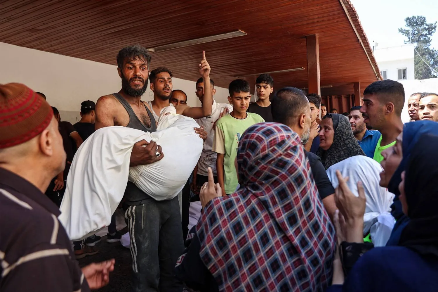 فلسطيني يحمل جثمان شخص قُتل خلال غارة إسرائيلية على مستودع لتوزيع المساعدات في حي الصبرة (أ.ف.ب)