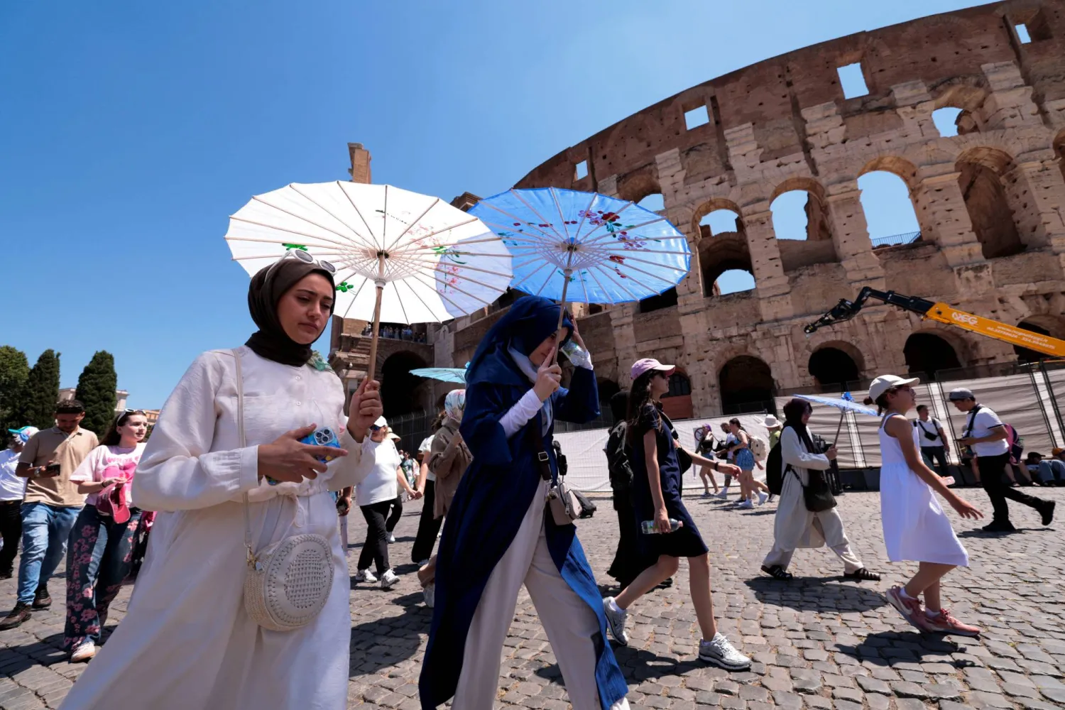 يتجول السياح بالمظلات أثناء زيارتهم للكولوسيوم خلال موجة حر في روما (رويترز)