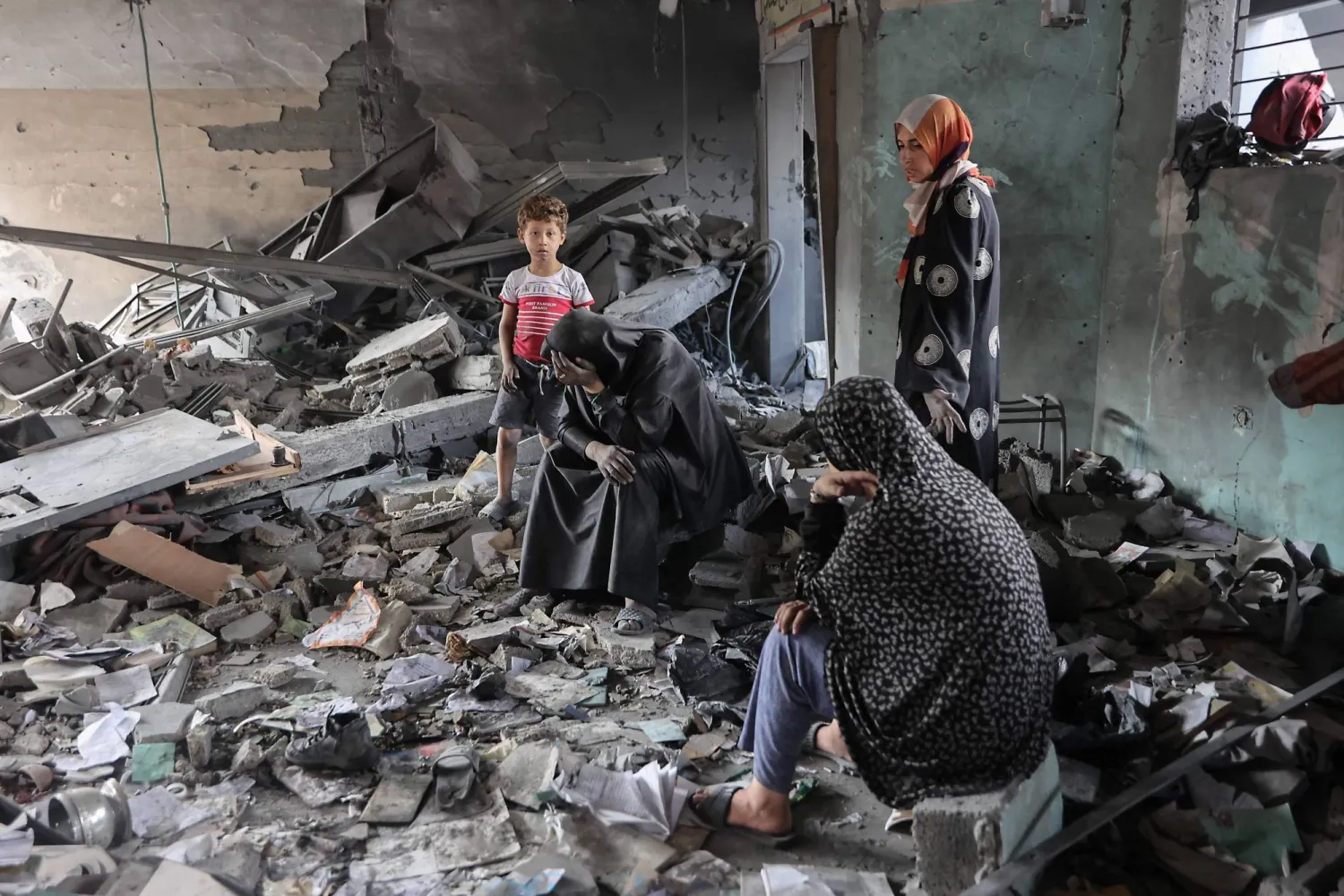 نساء فلسطينيات وسط دمار خلّفته ضربات إسرائيلية على مدرسة يافا بحي التفاح في مدينة غزة أمس (أ.ف.ب)