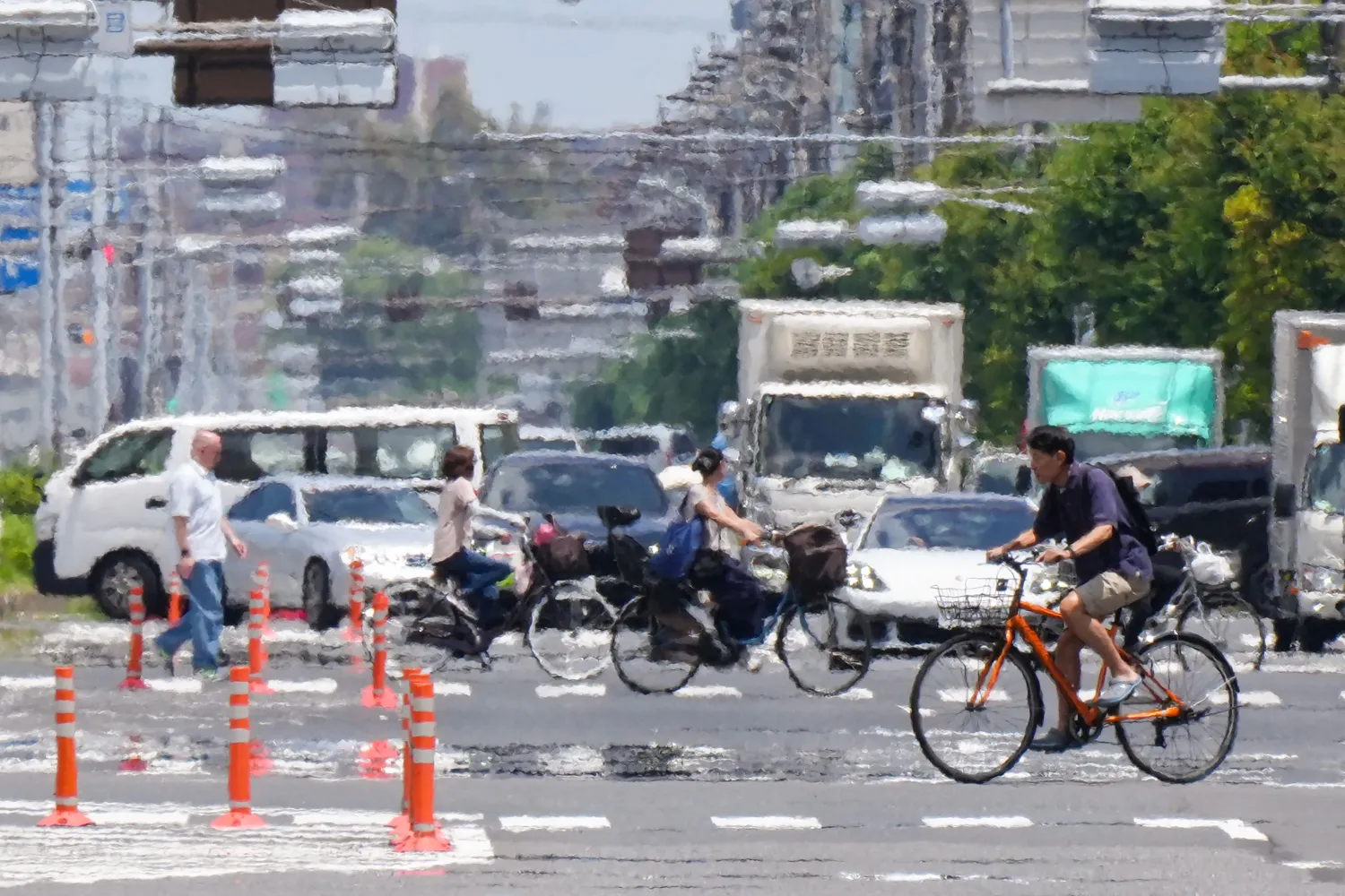 People on bicycles cross a street under the hot sun in Tokyo on June 20, 2025. (Photo by Kazuhiro NOGI / AFP)