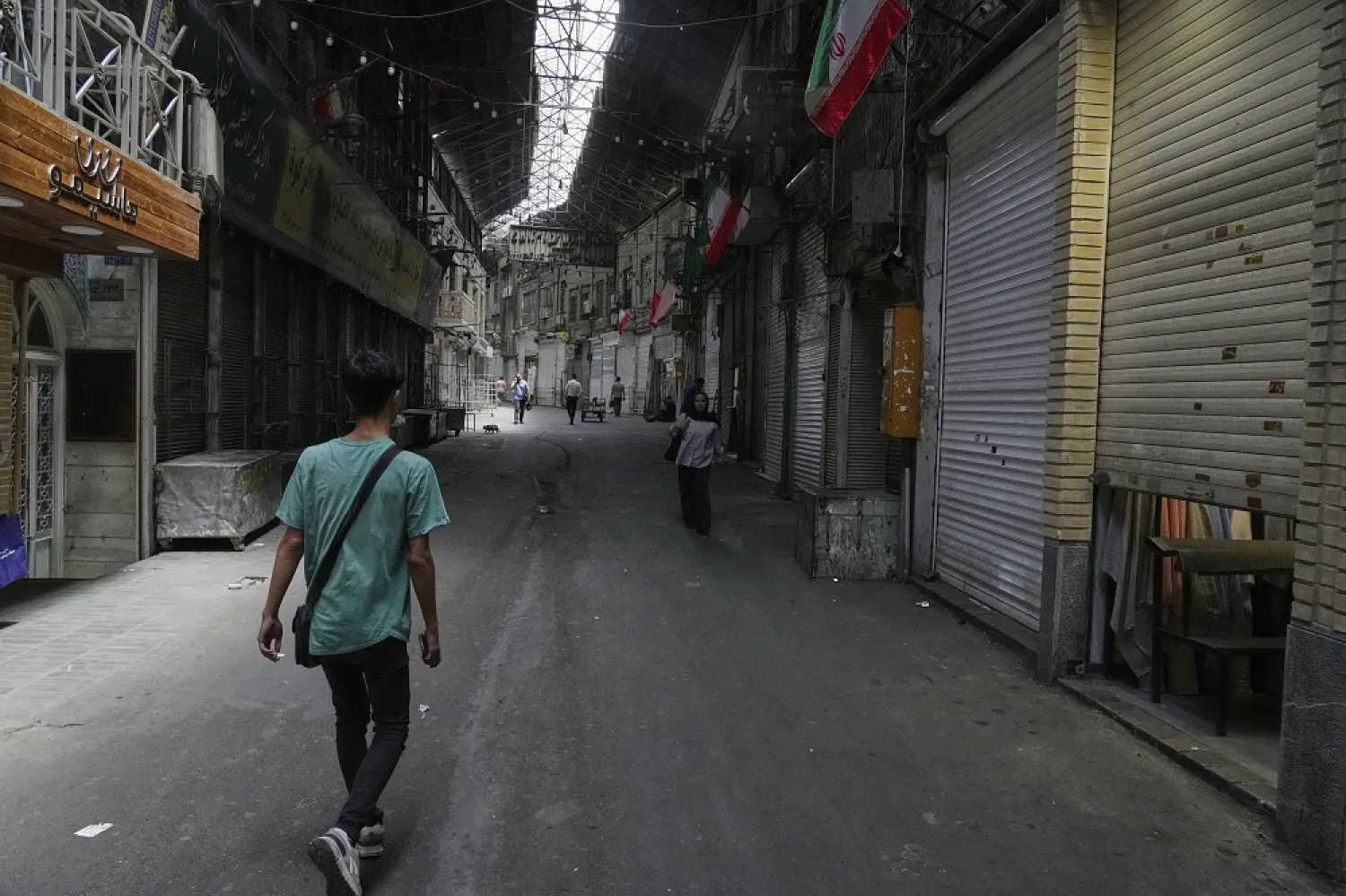 Few pedestrians walk along the historic Grand Bazaar as shops remain shuttered, in Tehran, Iran, Monday, June 16, 2025. (AP) 