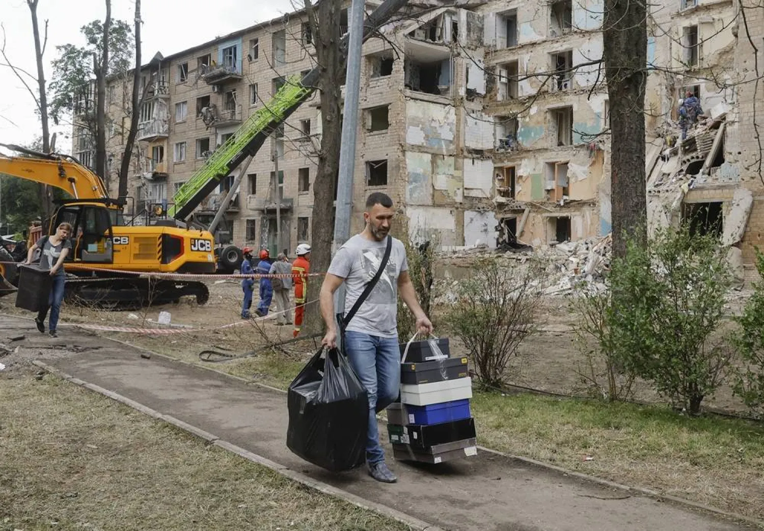 Local people carry their things from damaged flats at the site of a rocket strike on a five-storey residential building on 23 June, in Kyiv, Ukraine, 24 June 2025. (EPA)