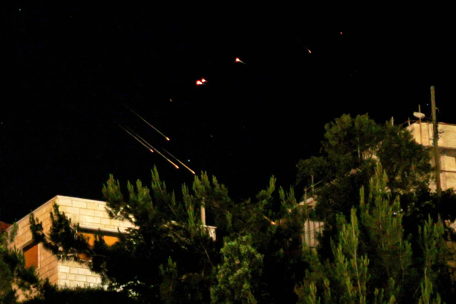 Debris of missiles fired from Iran toward Israel leave trails in the night sky over the Israel-annexed Golan Heights after being intercepted on June 13, 2025. (Photo by Jalaa MAREY / AFP)