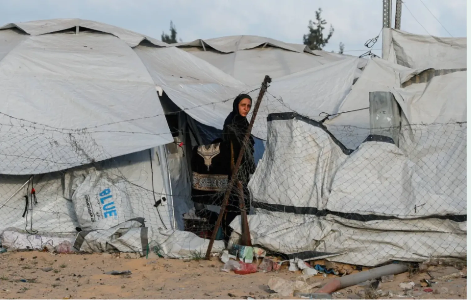 فلسطينية تقف بين خيام النازحين في خان يونس بجنوب قطاع غزة (رويترز)