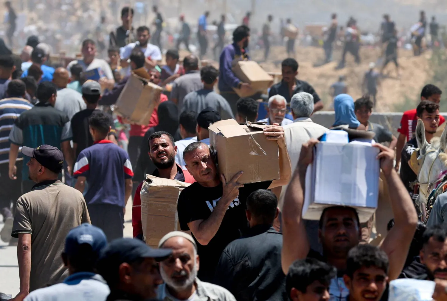 فلسطينيون يحملون إمدادات مساعدات تلقوها من مؤسسة غزة الإنسانية المدعومة من الولايات المتحدة في وسط قطاع غزة (رويترز) 