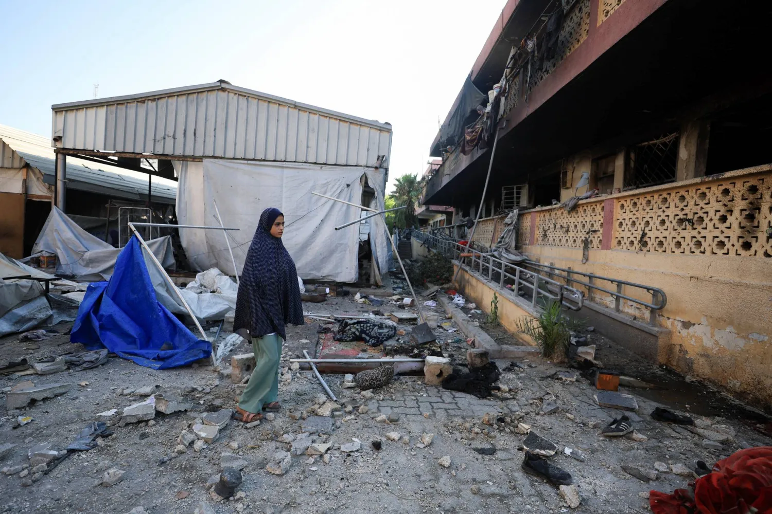 فتاة فلسطينية تتفقد الدمار الذي لحق بمدرسة تؤوي نازحين في غزة بعد تعرضها لقصف إسرائيلي (رويترز)