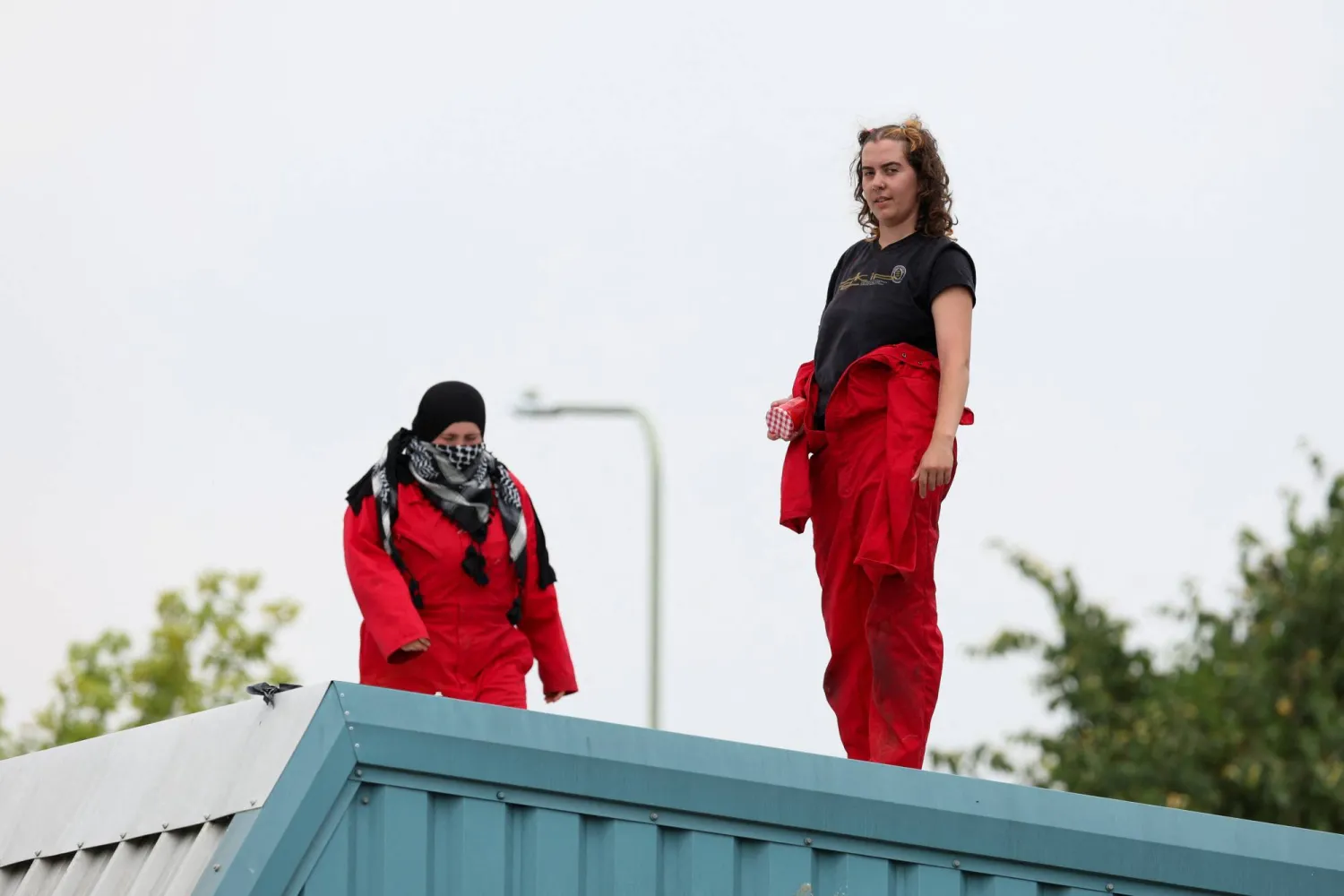 محتجون داعمون للفلسطينيين وحركة «فلسطين أكشن» فوق مبنى مجموعة «غارد تك» في بريطانيا (رويترز) 