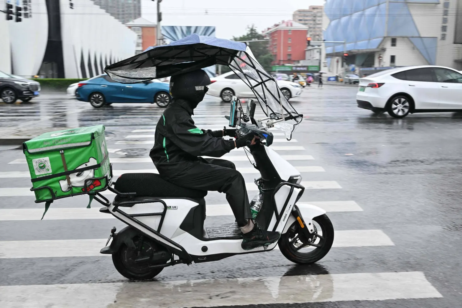 عامل توصيل للطلبات على دراجة نارية في أحد شوارع العاصمة الصينية بكين (أ ف ب)