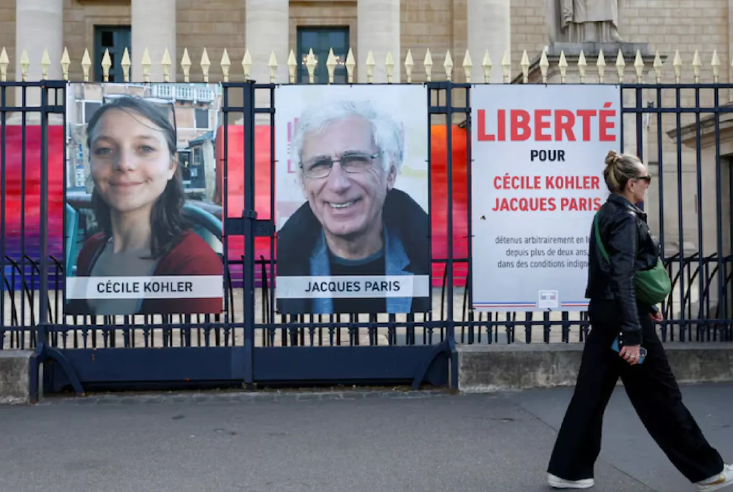 A woman walks past posters with the portraits of Cecile Kohler and Jacques Paris, two French citizens held in Iran, on the day of support rallies to mark their three-year detention and to demand their release, in front of the National Assembly in Paris, France, May 7, 2025. The slogan reads "Freedom for Cecile Kohler and Jacques Paris". REUTERS/Abdul Saboor/File Photo 