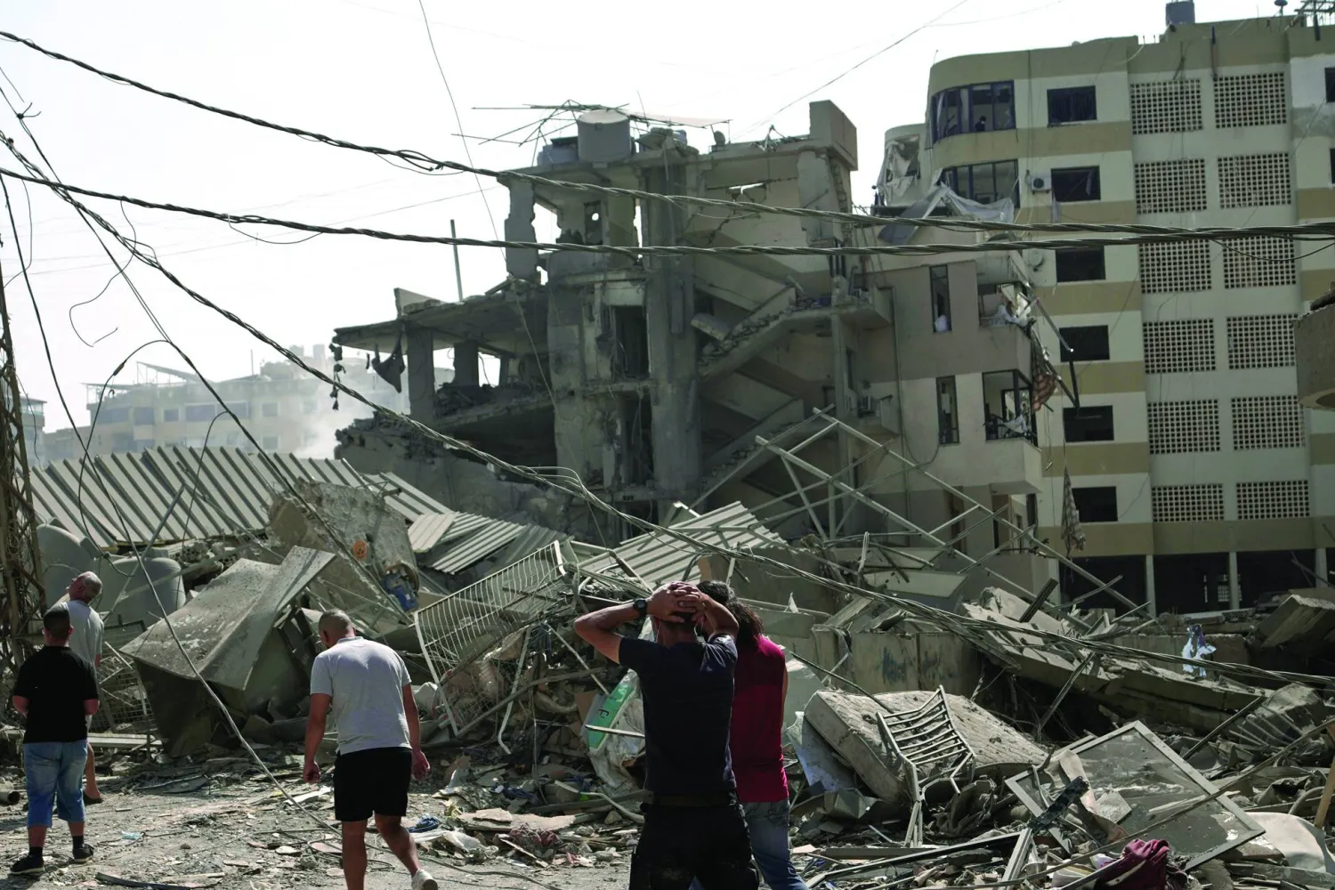 لبنانيون يتفقدون الدمار الناتج عن قصف إسرائيلي استهدف الضاحية الجنوبية الشهر الماضي (أ.ب)