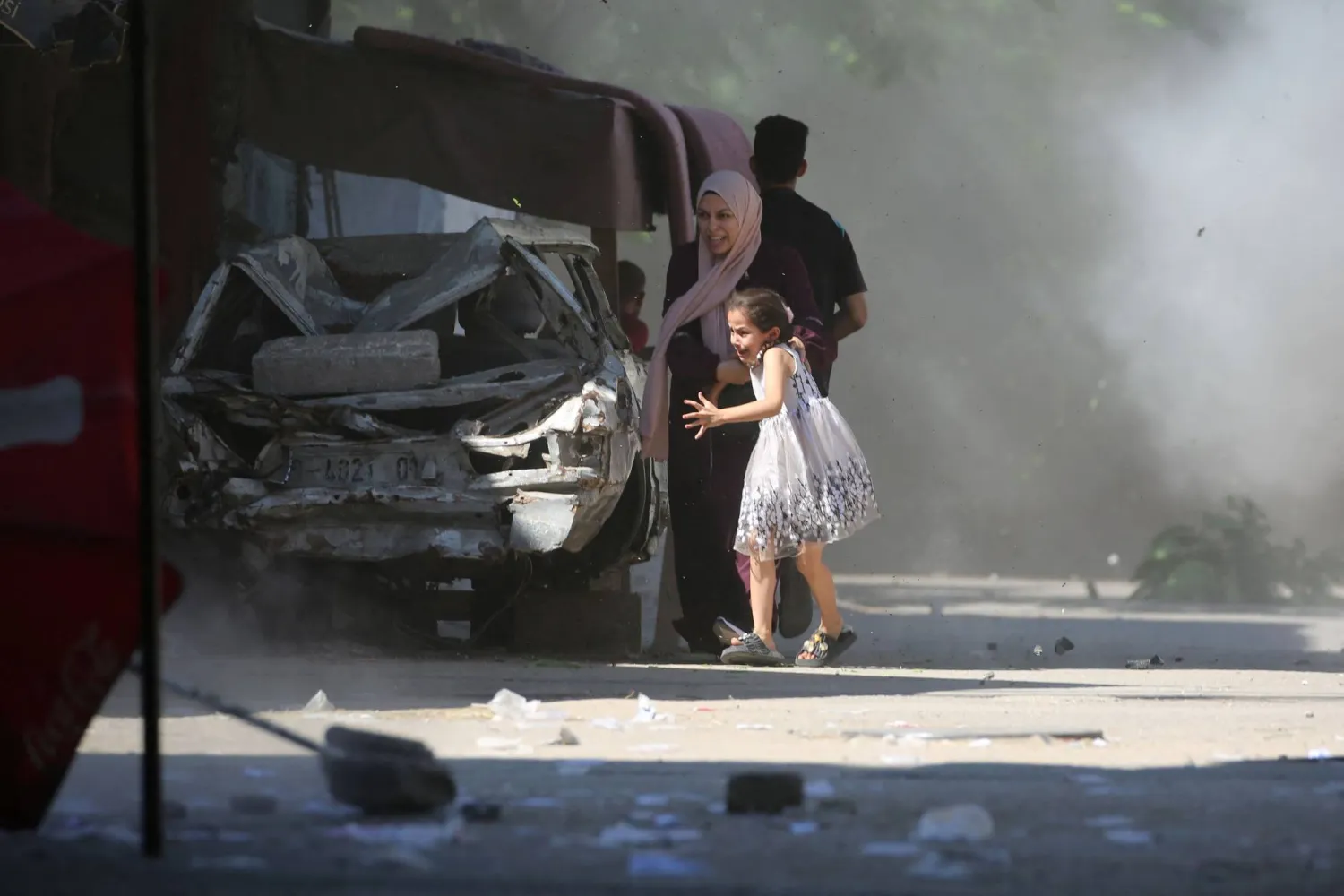 TOPSHOT - A Palestinian mother and her daughter rush for cover during an Israeli strike in the Al-Bureij camp in the central Gaza Strip on July 4, 2025. (Photo by Eyad BABA / AFP)