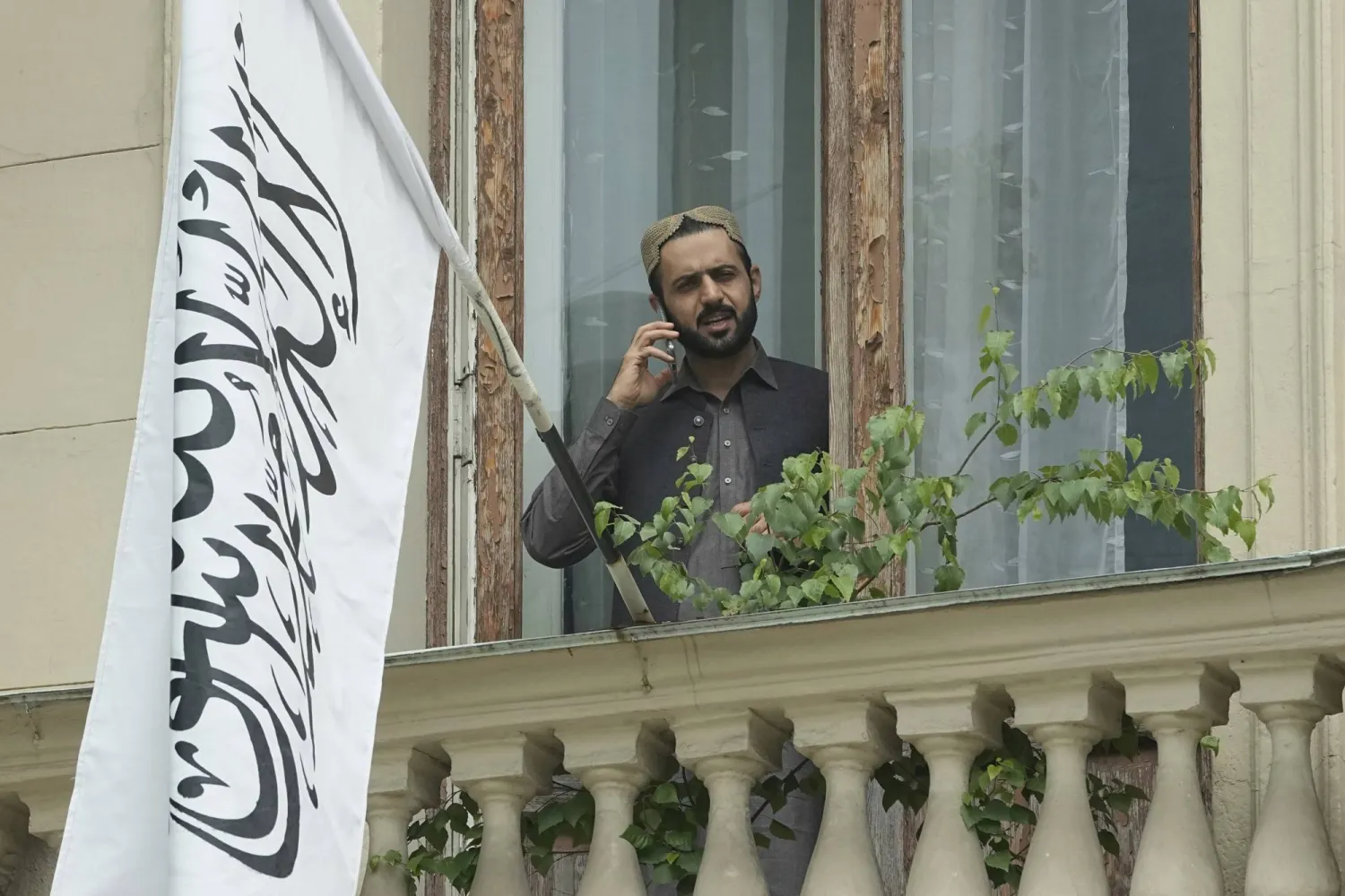 A man talks by a phone while standing on a balcony of the Afghan Embassy in Moscow, Russia, Friday, July 4, 2025, after Russia recognized the Taliban government in Afghanistan. (AP Photo/Pavel Bednyakov)