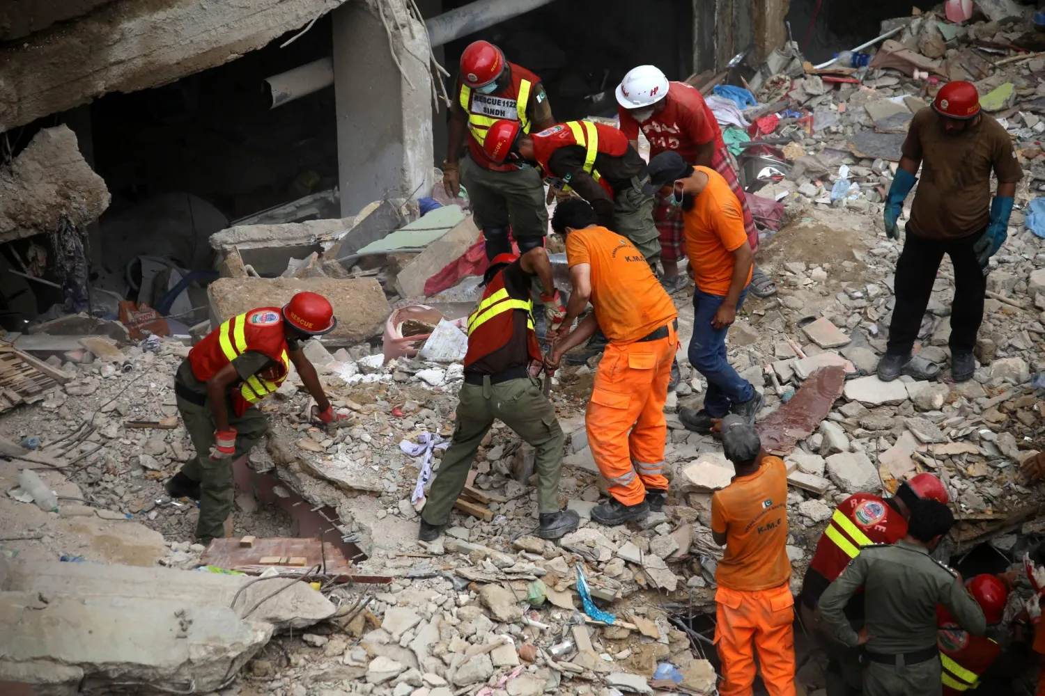 عمّال إنقاذ يبحثون بين أنقاض المبنى المنهار في كراتشي (إ.ب.أ)