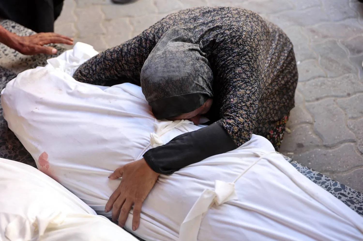 فلسطينية تحتضن جثمان أحد أقربائها قُتل في غارة إسرائيلية على مستودع لتوزيع المساعدات الإنسانية وسط غزة (أ.ف.ب)