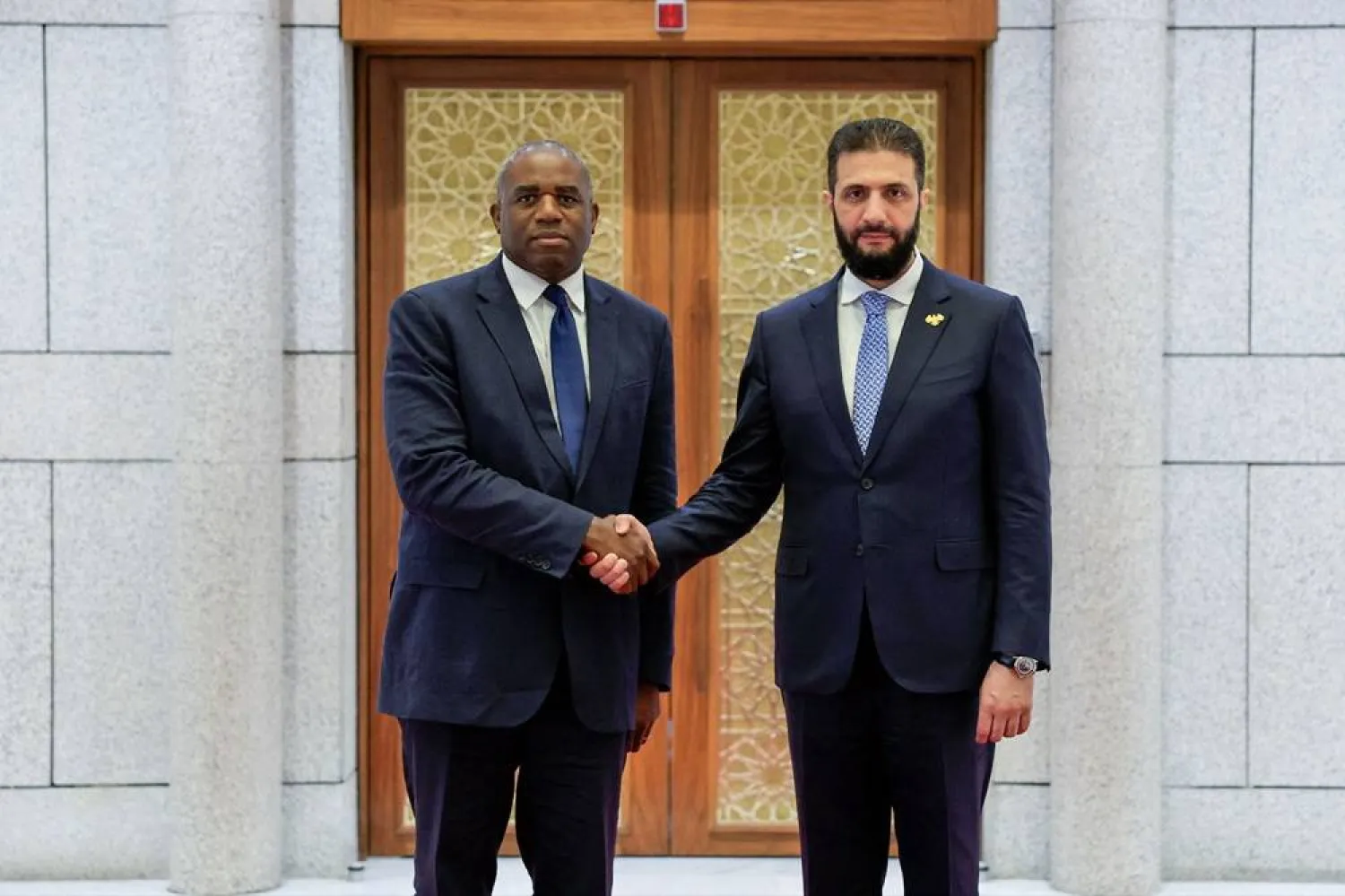 A handout picture released by the official Syrian Arab News Agency (SANA) shows Syria's interim President Ahmed al-Sharaa (R) welcoming with British Foreign Secretary David Lammy in the Syrian capital Damascus on July 5, 2025. (SANA / AFP) 