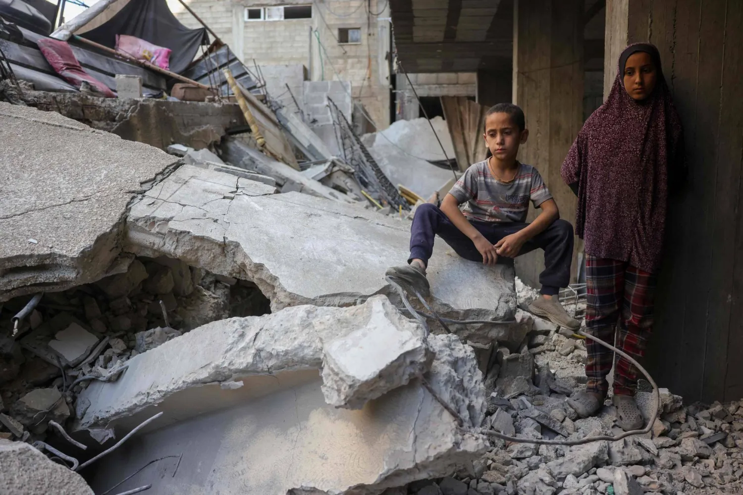 أطفال فلسطينيون يراقبون الناس وهم يبحثون عن ناجين بين أنقاض مبنى في حي الشيخ رضوان بمدينة غزة وسط القطاع (أ.ف.ب)