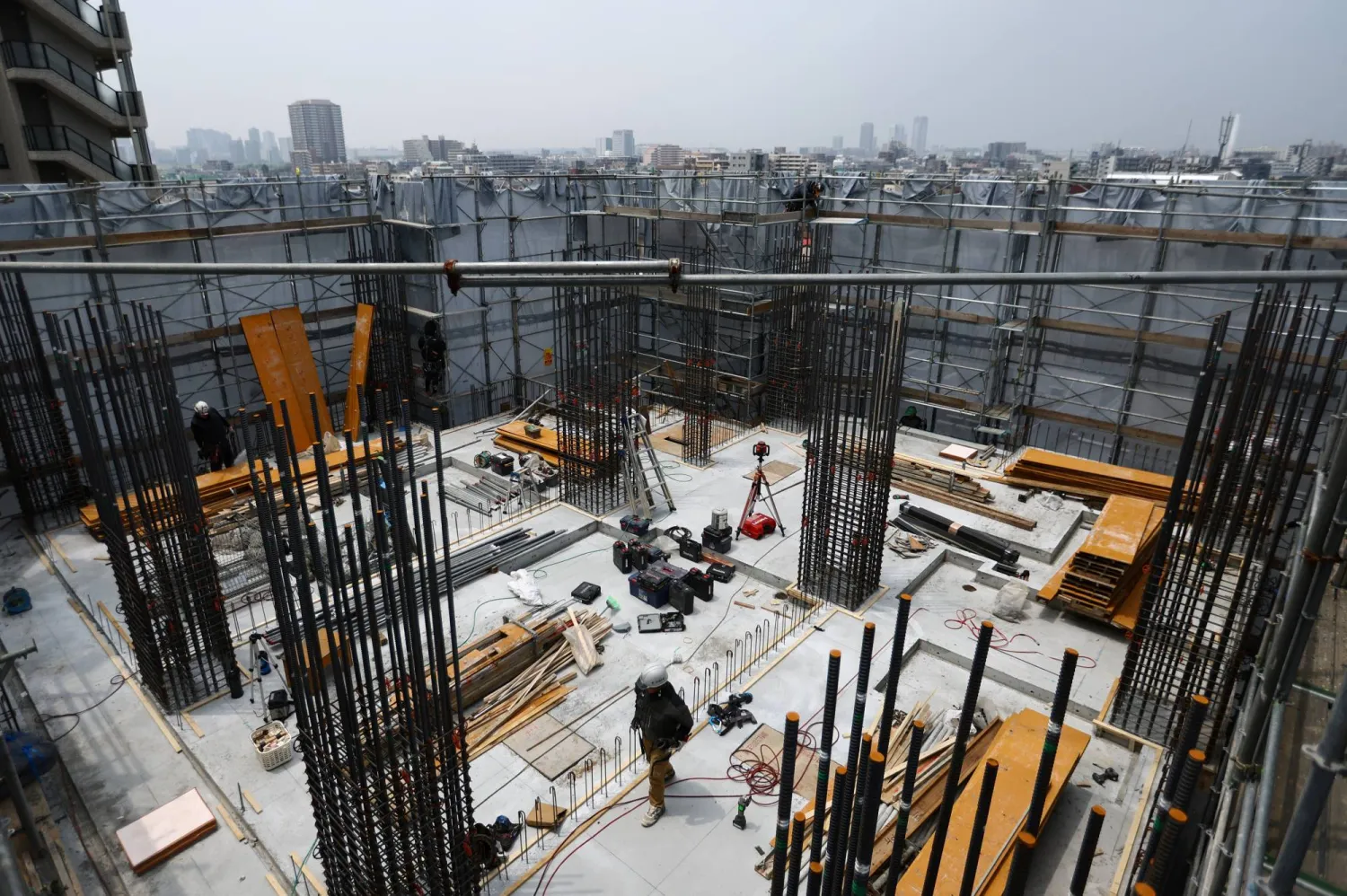 عمال فوق إحدى العمارات قيد الإنشاء بالعاصمة اليابانية طوكيو (رويترز)