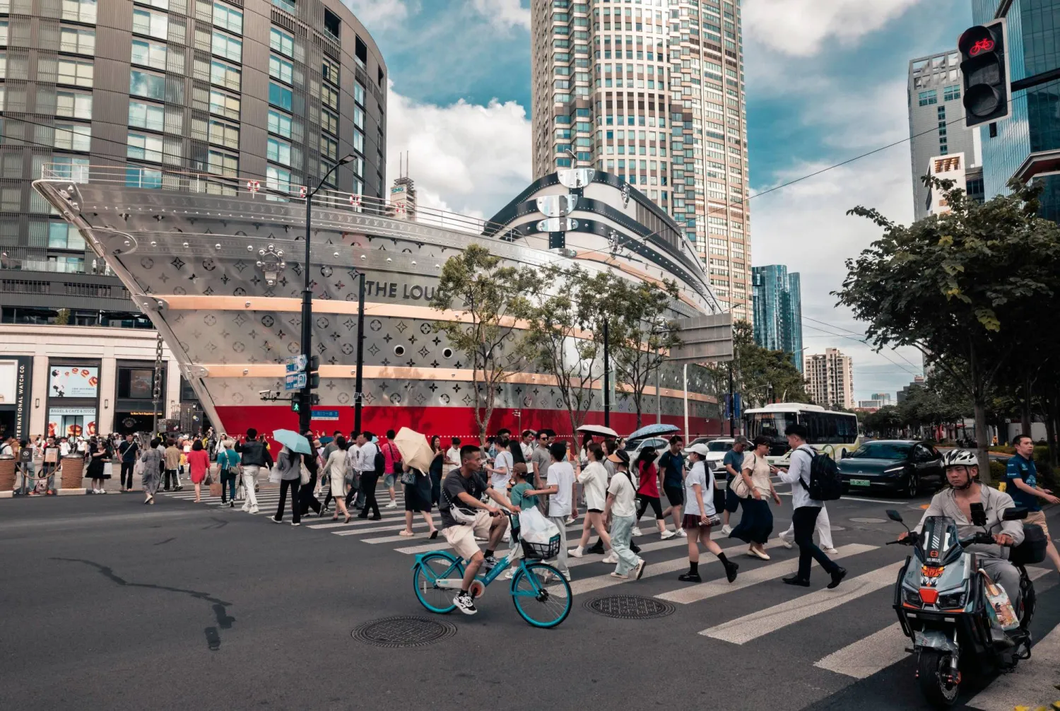 مشاة يعبرون الطريق أمام مركز تجاري ضخم في مدينة شنغهاي الصينية (إ.ب.أ)