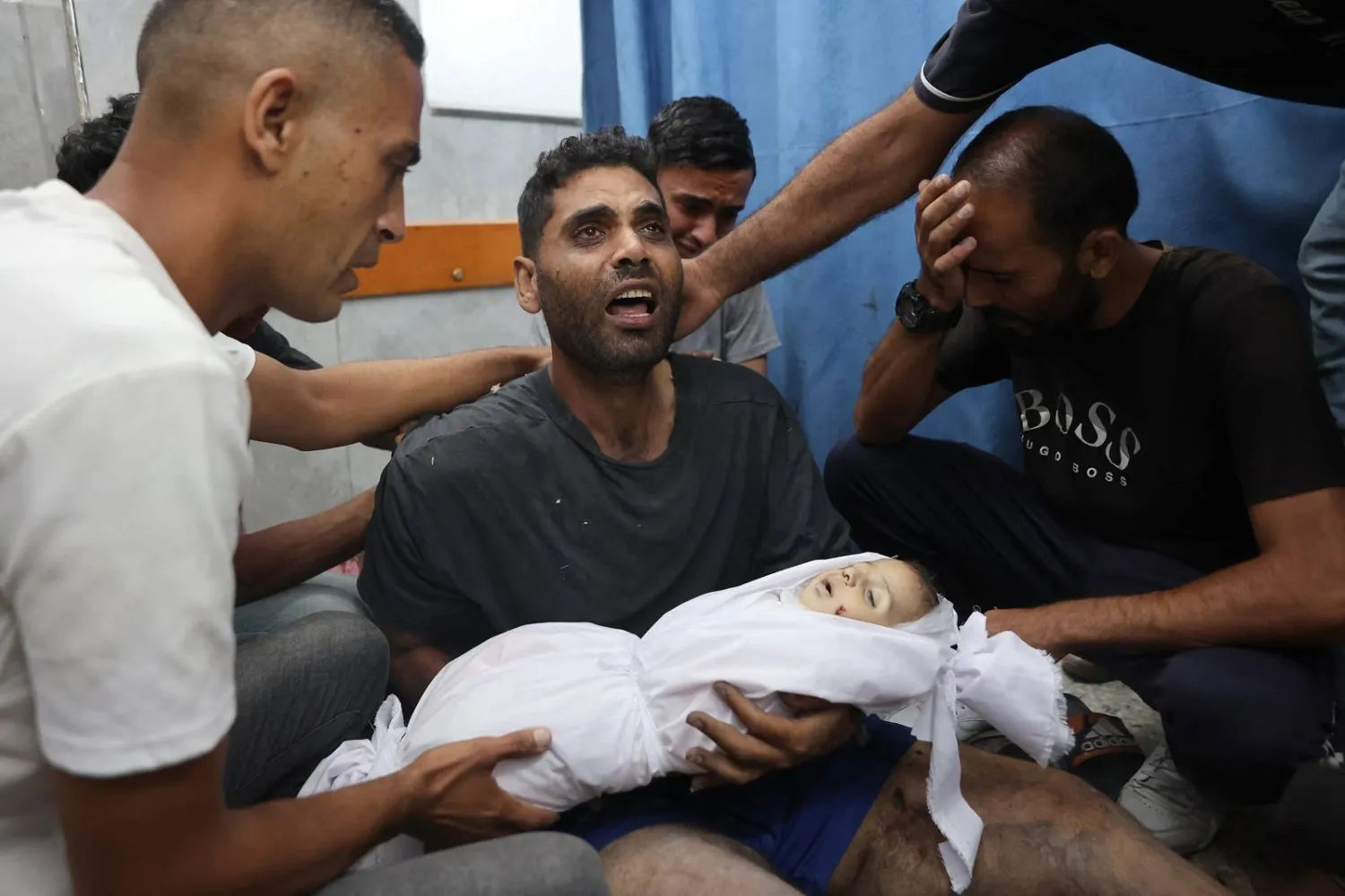 شاب فلسطيني يحمل جثمان ابنه الذي قُتل في غارة إسرائيلية جنوب غزة (أ.ف.ب)
