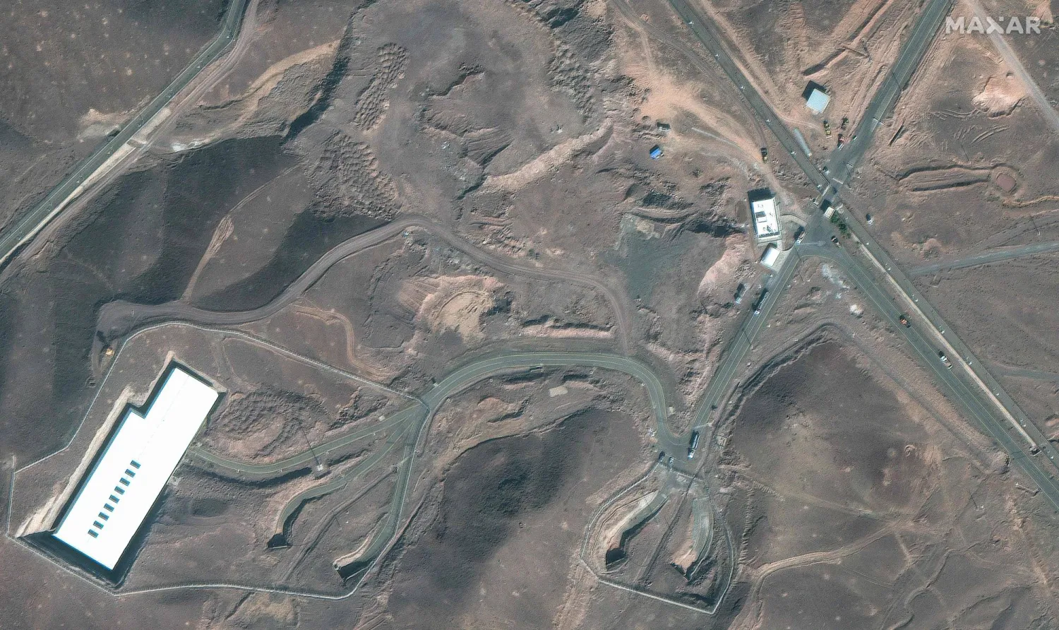 This handout satellite image courtesy of Maxar Technologies shows cargo trucks postioned near an underground entrance to Iran's Fordow Fuel Enrichment Plant (FFEP), in Fordo, Iran on June 20, 2025. (Photo by Satellite image 2025 Maxar Technologies / AFP) 