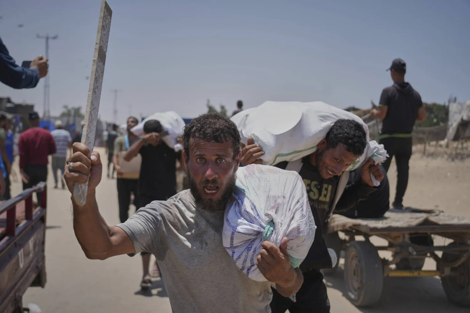 فلسطينيون يحملون أكياس الدقيق من «مؤسسة غزة الإنسانية» في رفح (أ.ب)