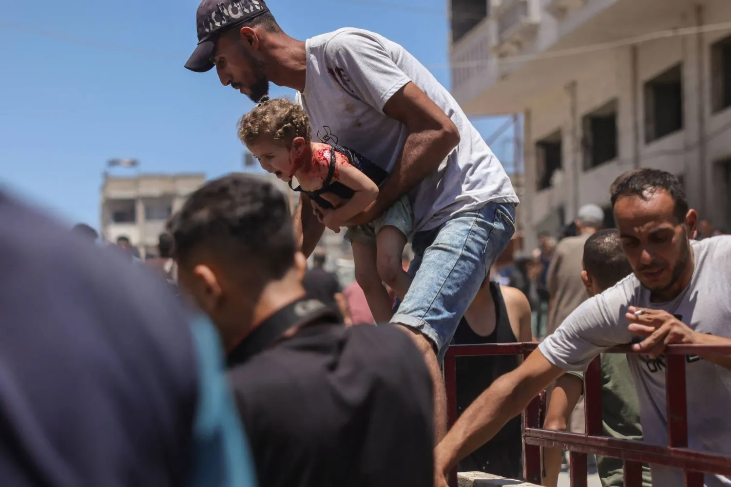 فلسطيني يحمل طفلة مصابة في موقع غارة إسرائيلية بجوار خيمة للنازحين في مدينة غزة يوم الثلاثاء (أ.ف.ب)
