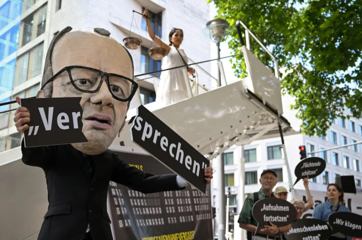 An activist depicting Chancellor Friedrich Merz shows a broken "promise" lettering in a symbolic protest action for the continuation of visa issuance under the admission programs for vulnerable Afghans, in connection with the first wave of lawsuits against the Federal Foreign Office and the suspending and reassess all refugee programs of the German government, in Berlin, Germany June 20, 2025. REUTERS/Annegret Hilse/File Photo 