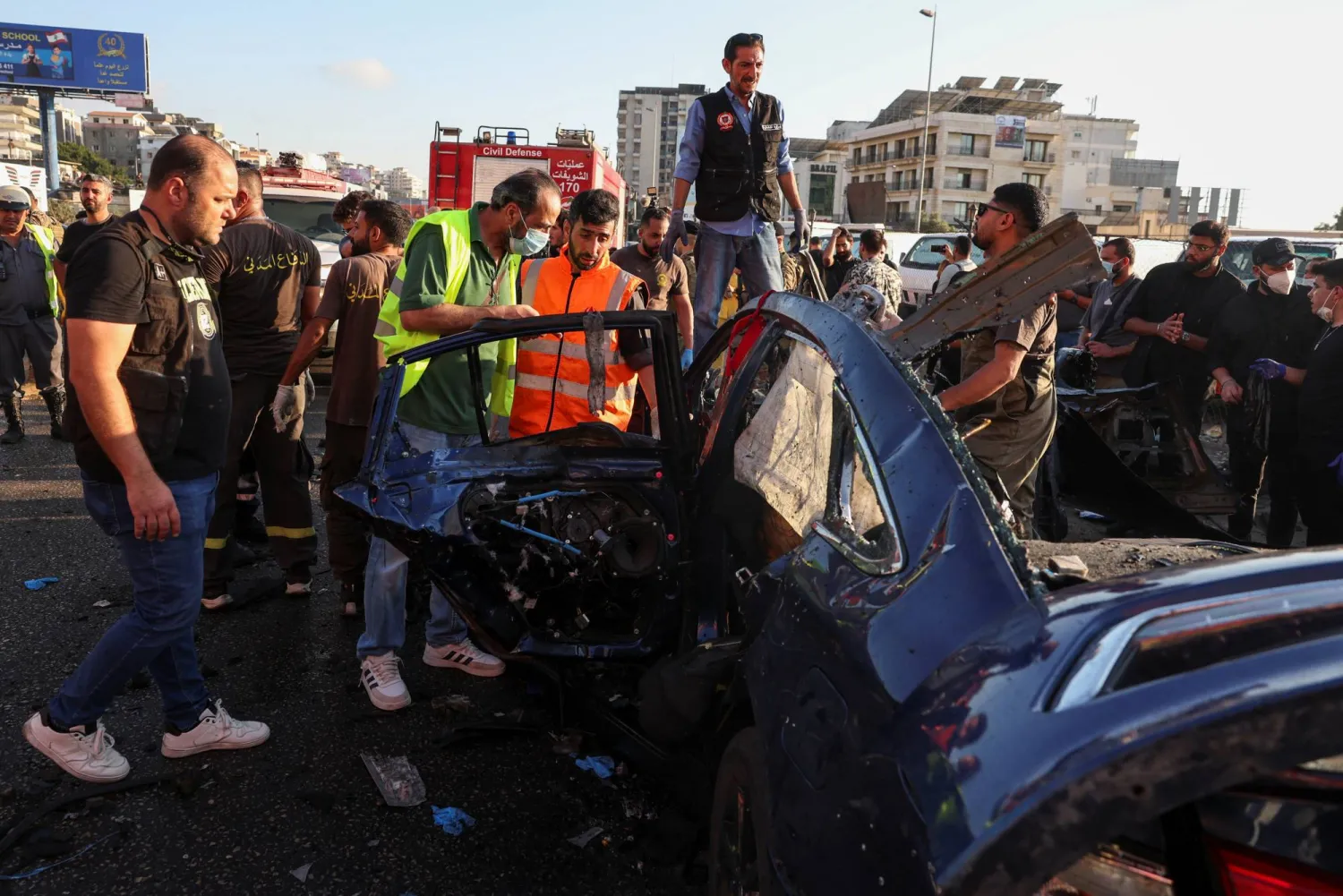 عناصر من الدفاع المدني يتجمعون بالقرب من سيارة استهدفتها غارة إسرائيلية في خلدة بلبنان (رويترز)