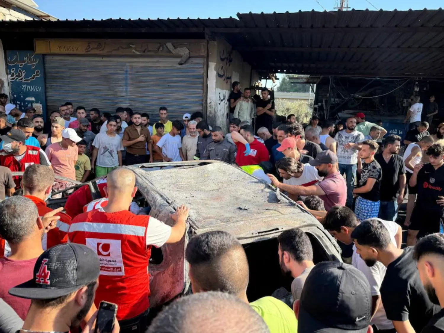 People gather near a damaged car after the Israeli military said in a statement that it struck a "key" figure from Palestinian militant group Hamas, in Ayrounieh, northern Lebanon July 8, 2025. REUTERS/Walid Saleh