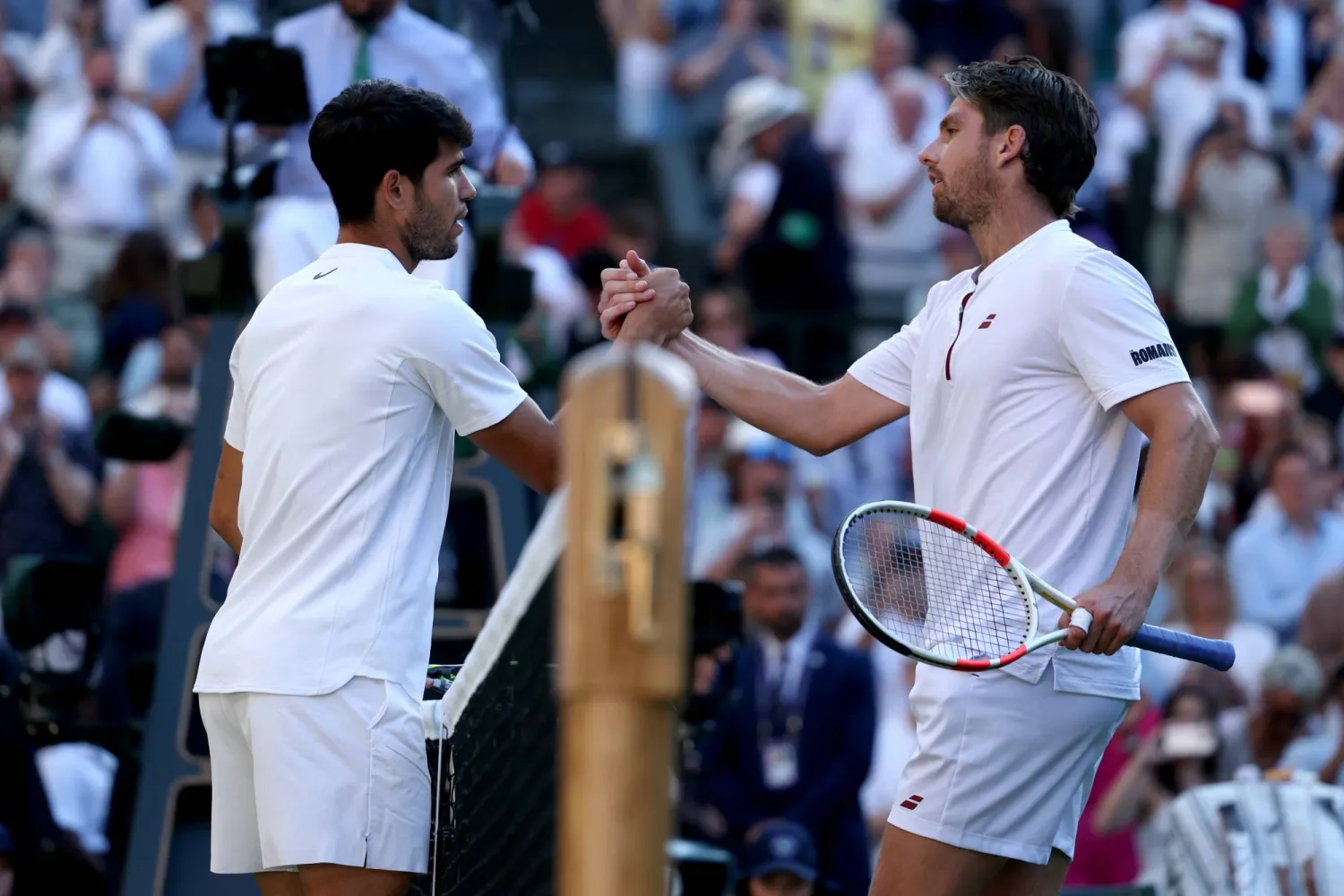 الإسباني كارلوس ألكاراس يصافح منافسه البريطاني كاميرون نوري عقب الفوز عليه في ويمبلدون (إ.ب.أ)