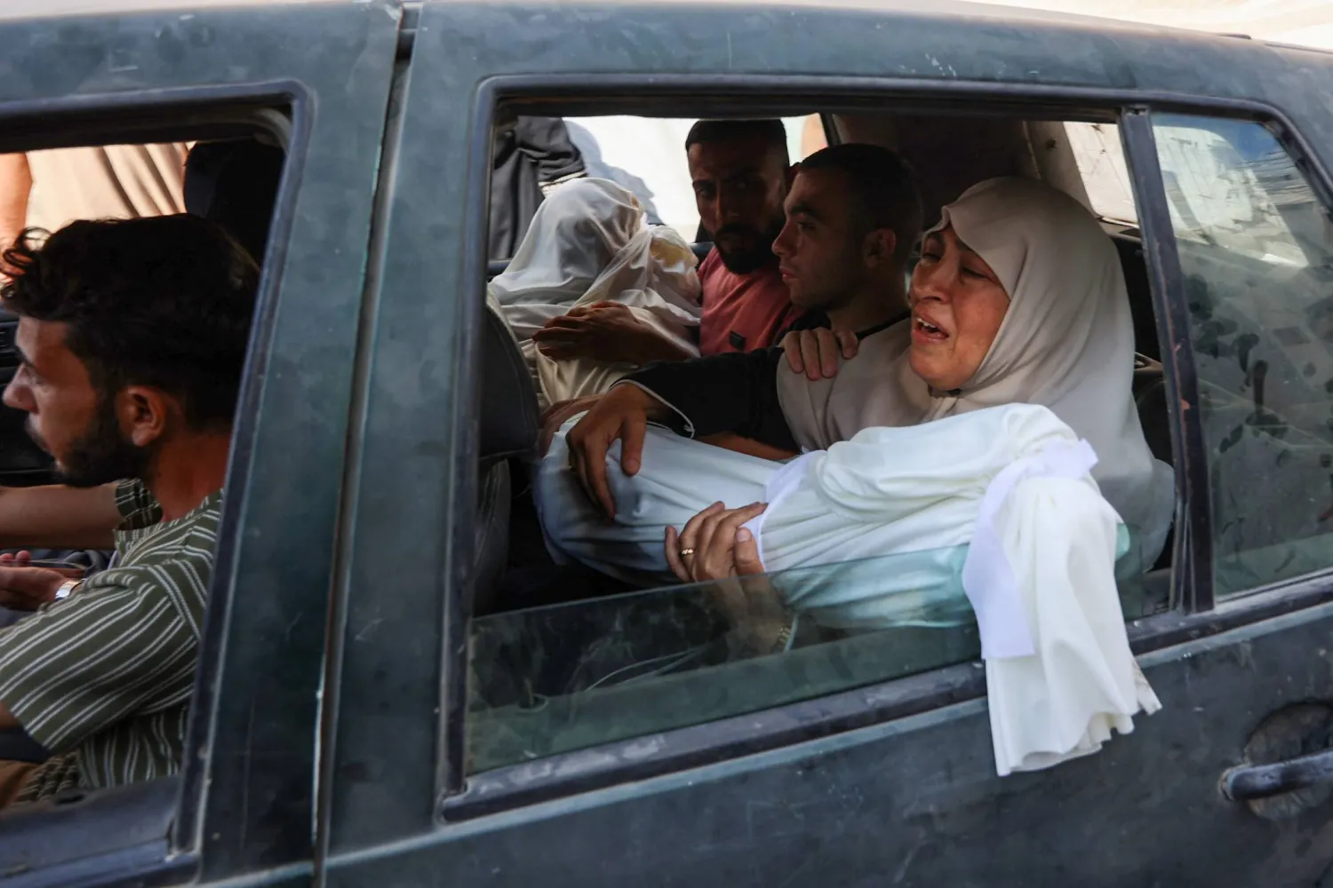 فلسطينية تحمل جثمان قريب لها قُتل بغارة إسرائيلية قبيل الجنازة في مدينة غزة أمس (أ.ف.ب)