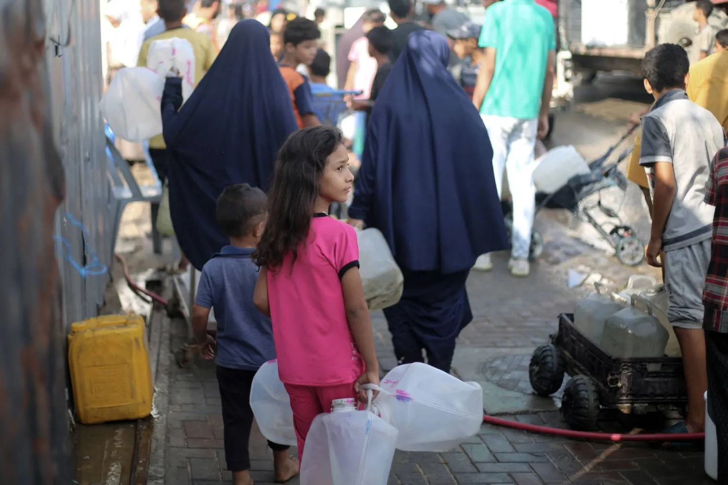 فلسطينيون يحصلون على المياه من نقطة توزيع بمخيم النصيرات للاجئين في وسط قطاع غزة (أ.ف.ب)