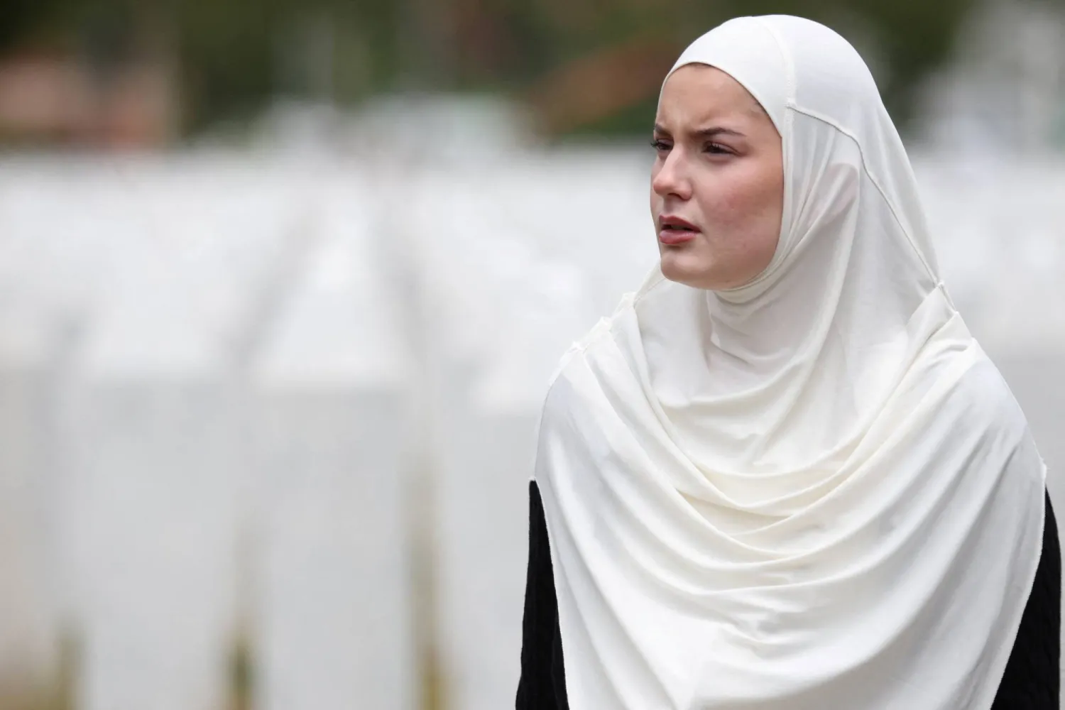 امرأة من البوسنة تبحث في مقبرة «بوتوكاري» التذكارية عن قبور أقربائها الذين قُتلوا في مذبحة «سريبرينيتسا»... (رويترز) 